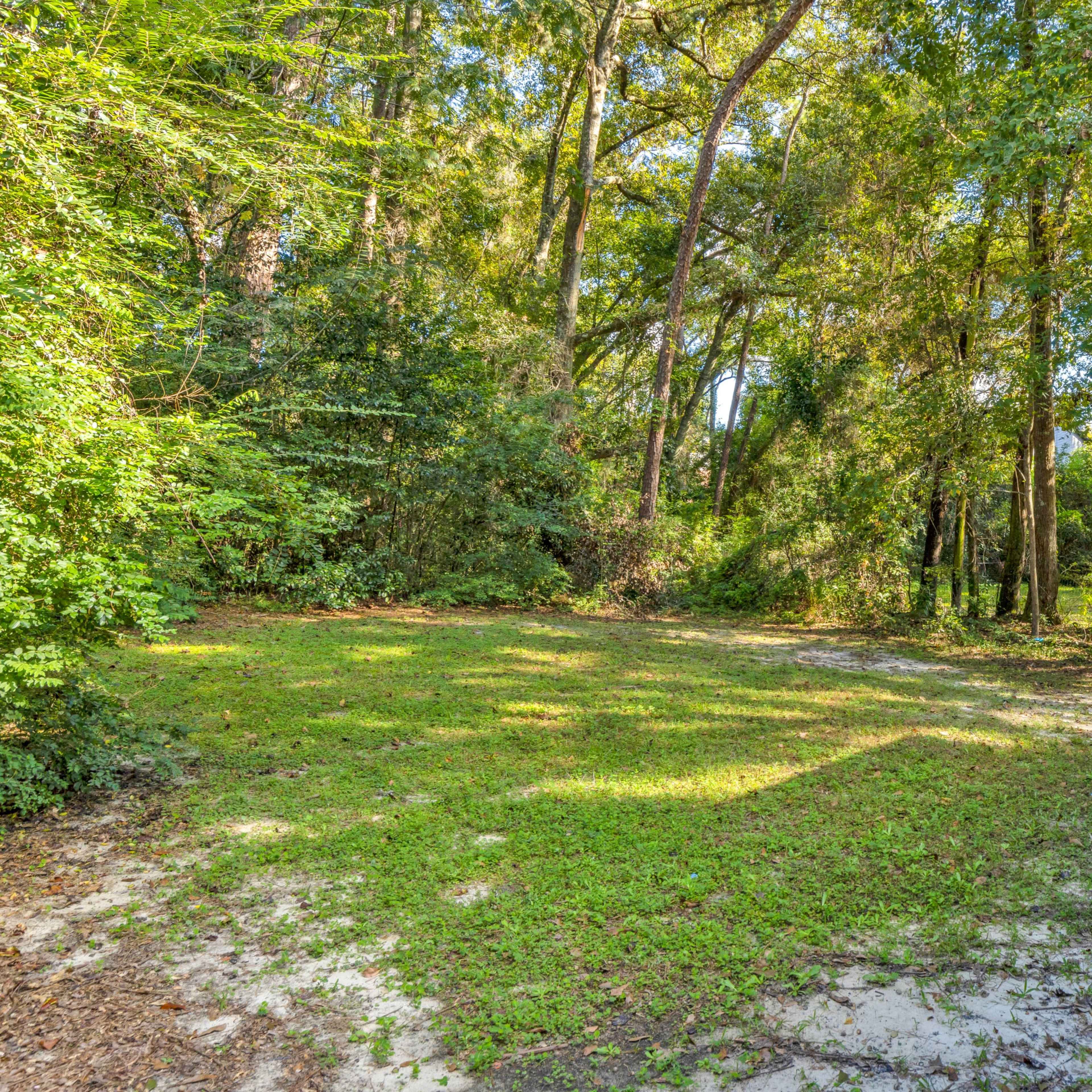 A cleared area of land surrounded by trees, adjacent to a building on the right.