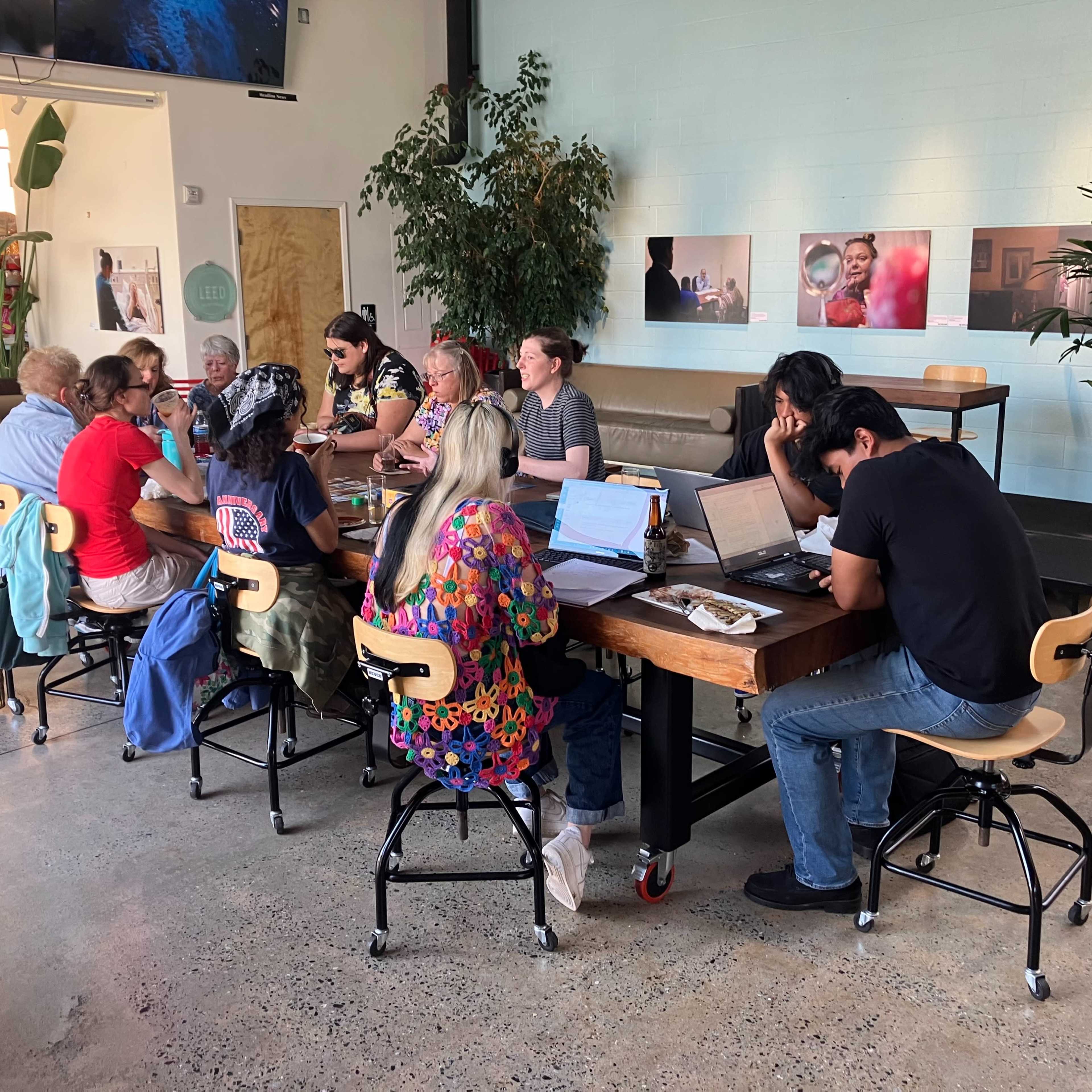 A diverse group of individuals collaborates around a large table in a modern workspace.