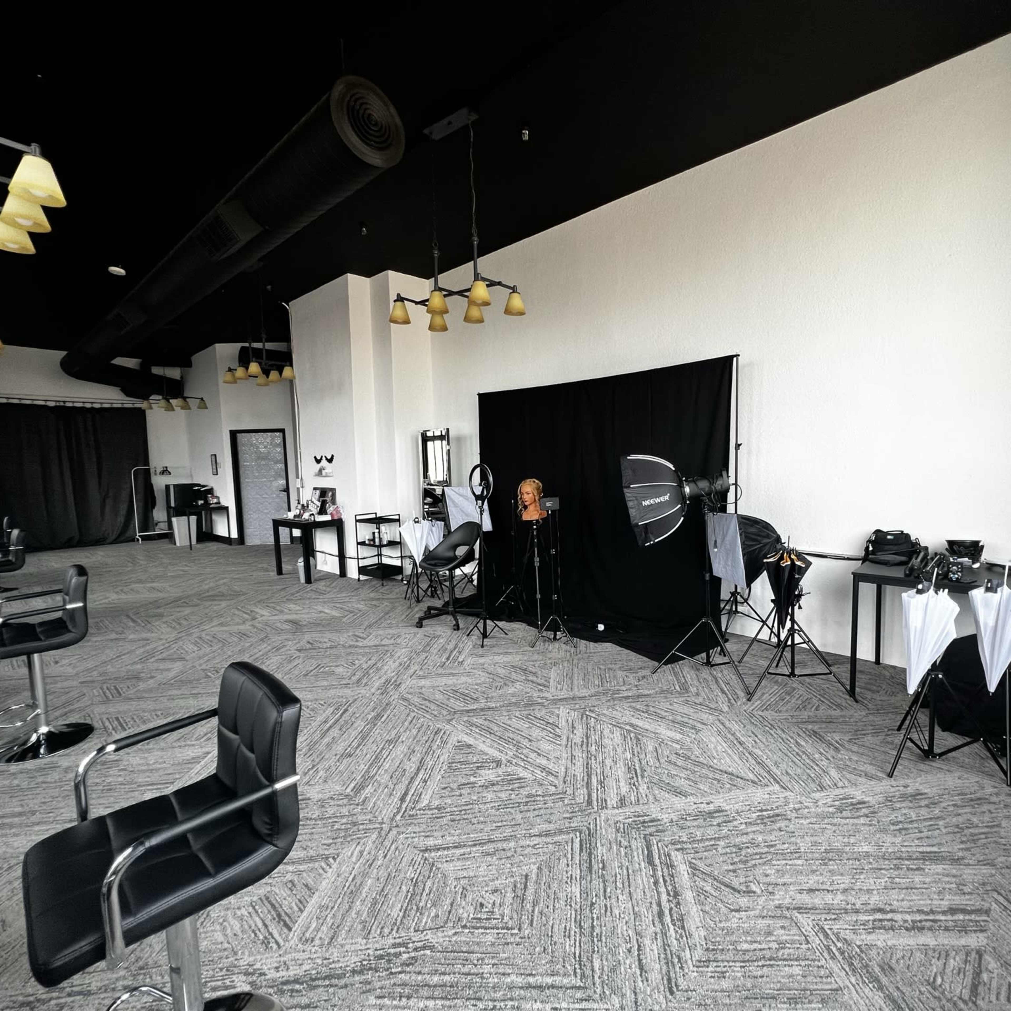 A spacious interior of a photography studio with equipment set up against a black backdrop.