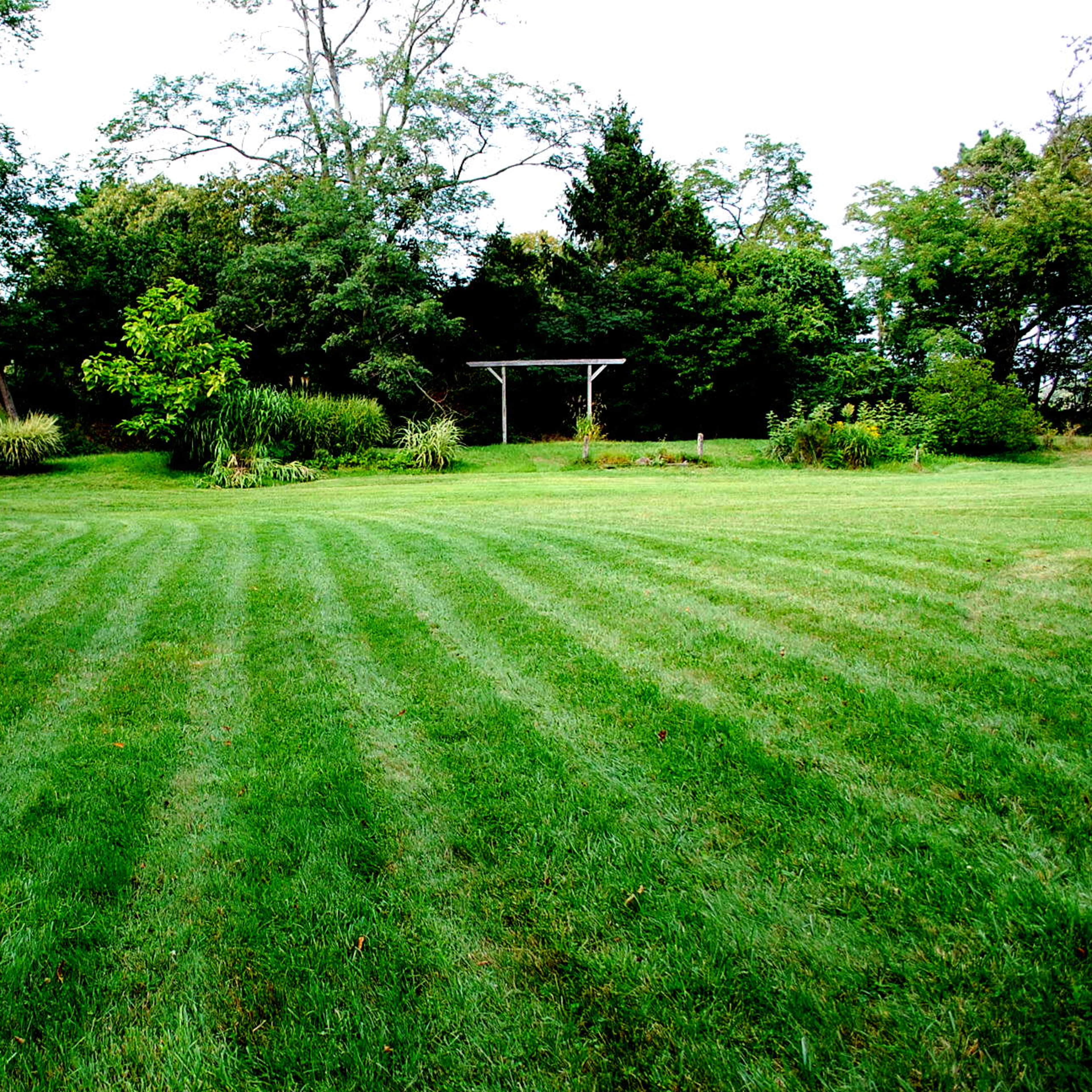 A landscaped lawn with neatly striped grass and a small garden area in the background.