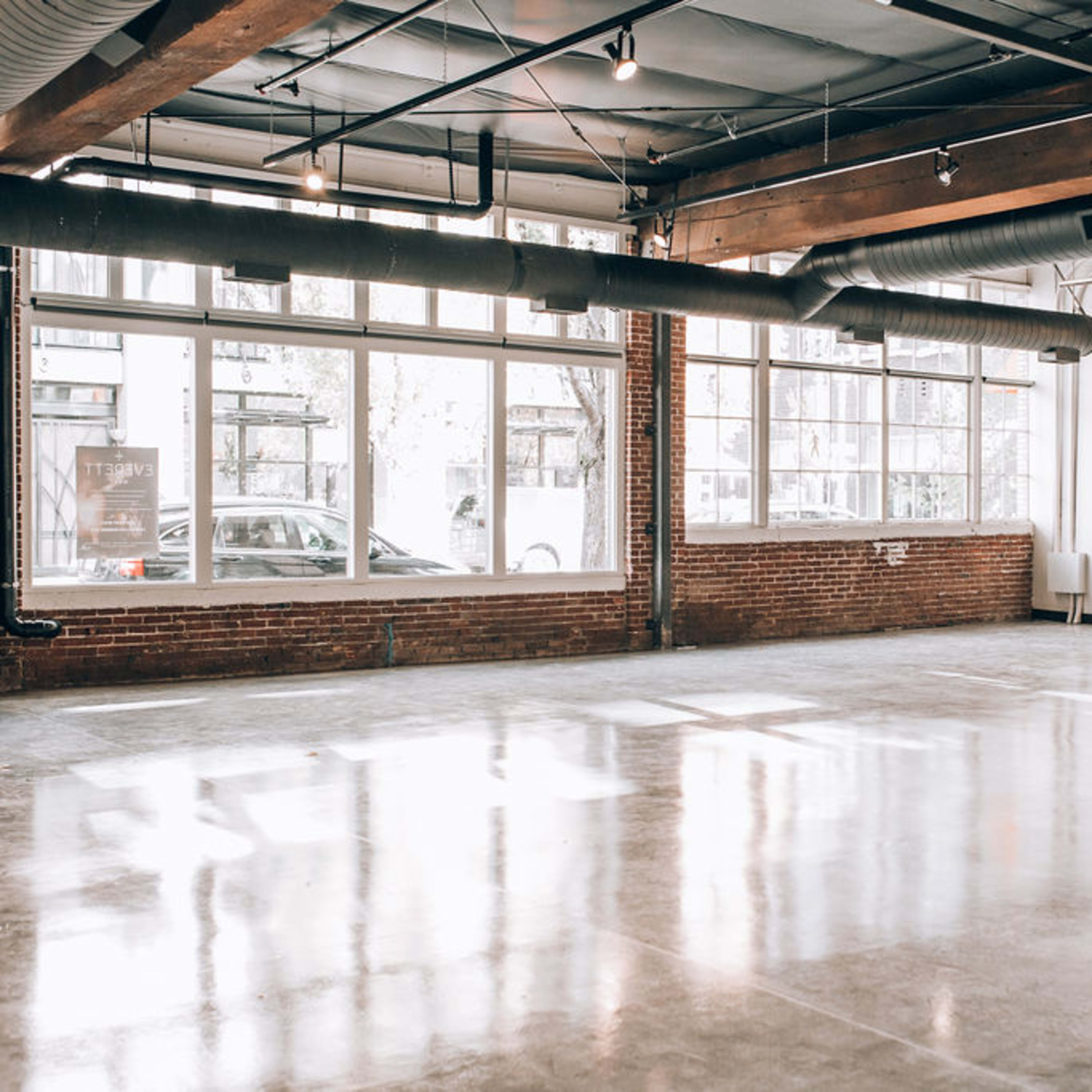 An empty, well-lit industrial space with large windows and polished concrete flooring.