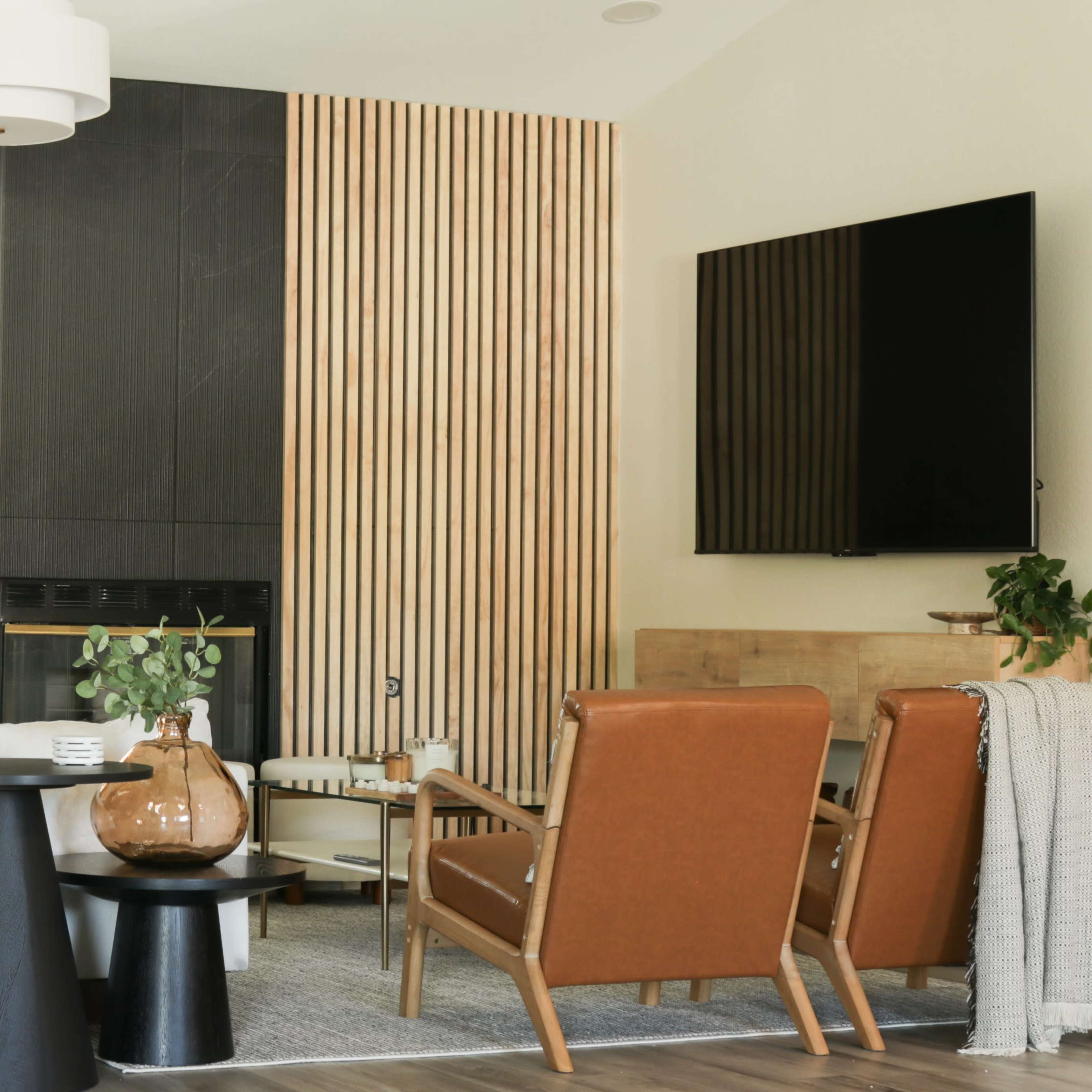 The living room features a modern design with a minimalist white sofa, brown leather chairs, a black side table, and a wooden accent wall.