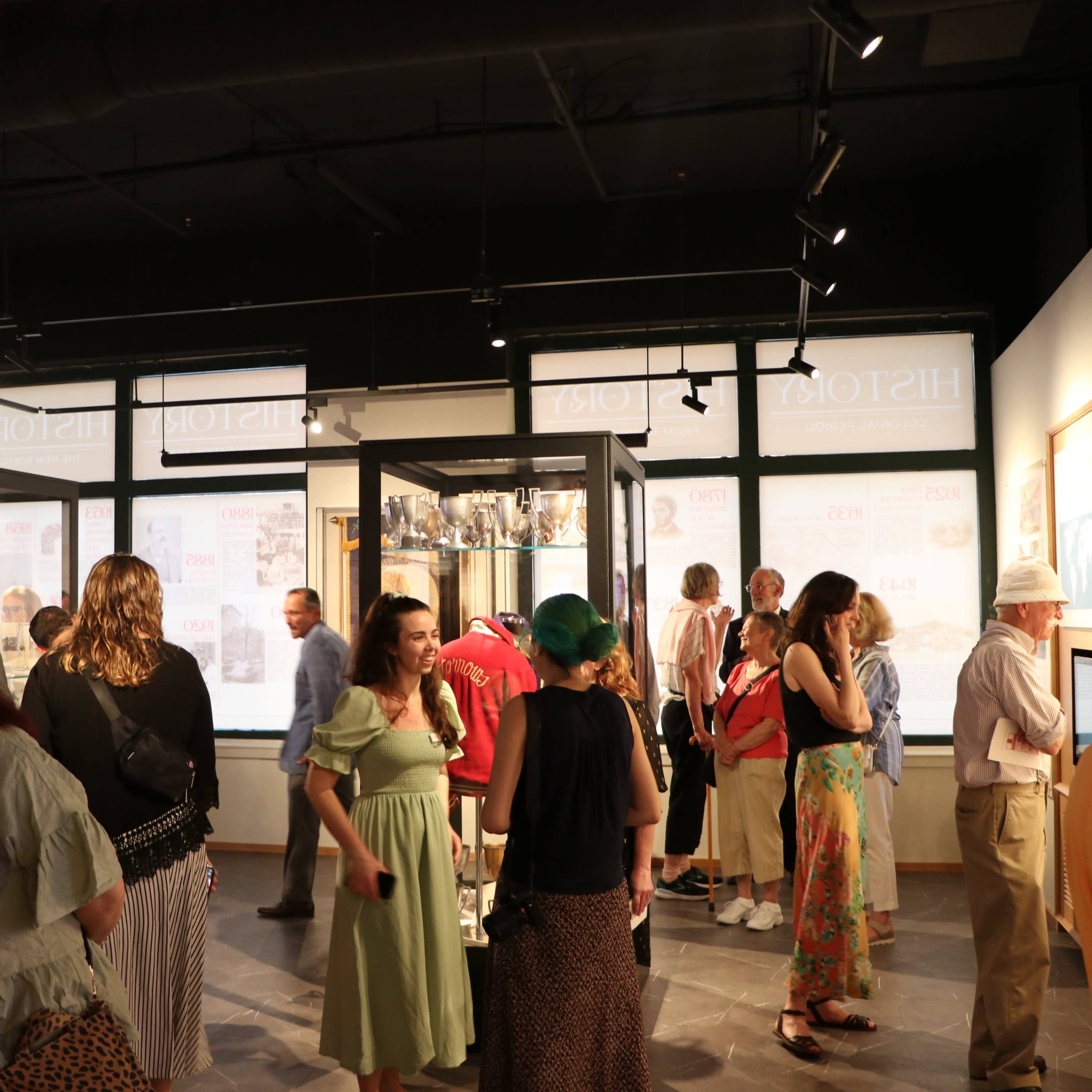 A group of people are exploring an exhibition space filled with display cases and informational panels.