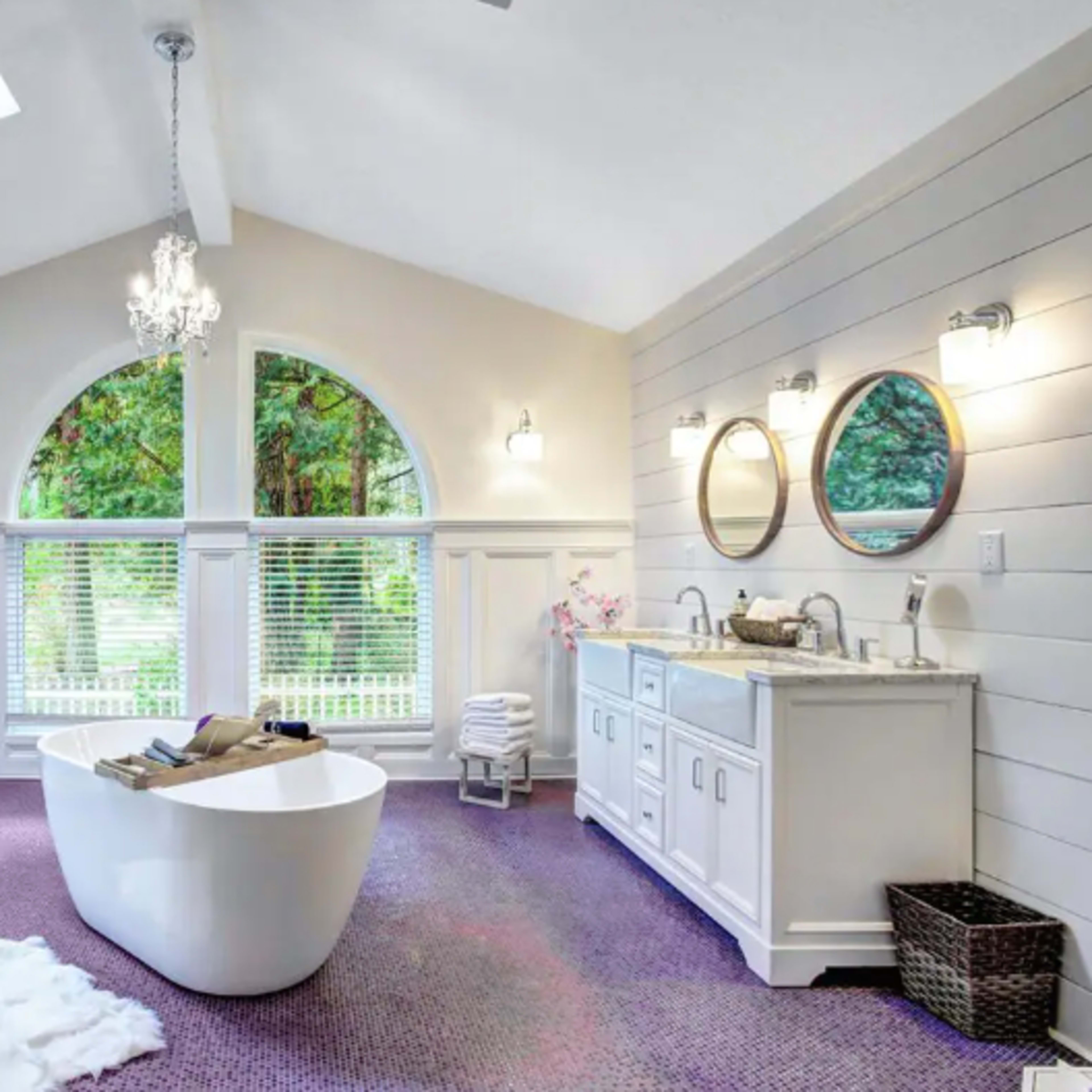 A bathroom with a freestanding tub, dual sinks, and large windows that let in natural light.