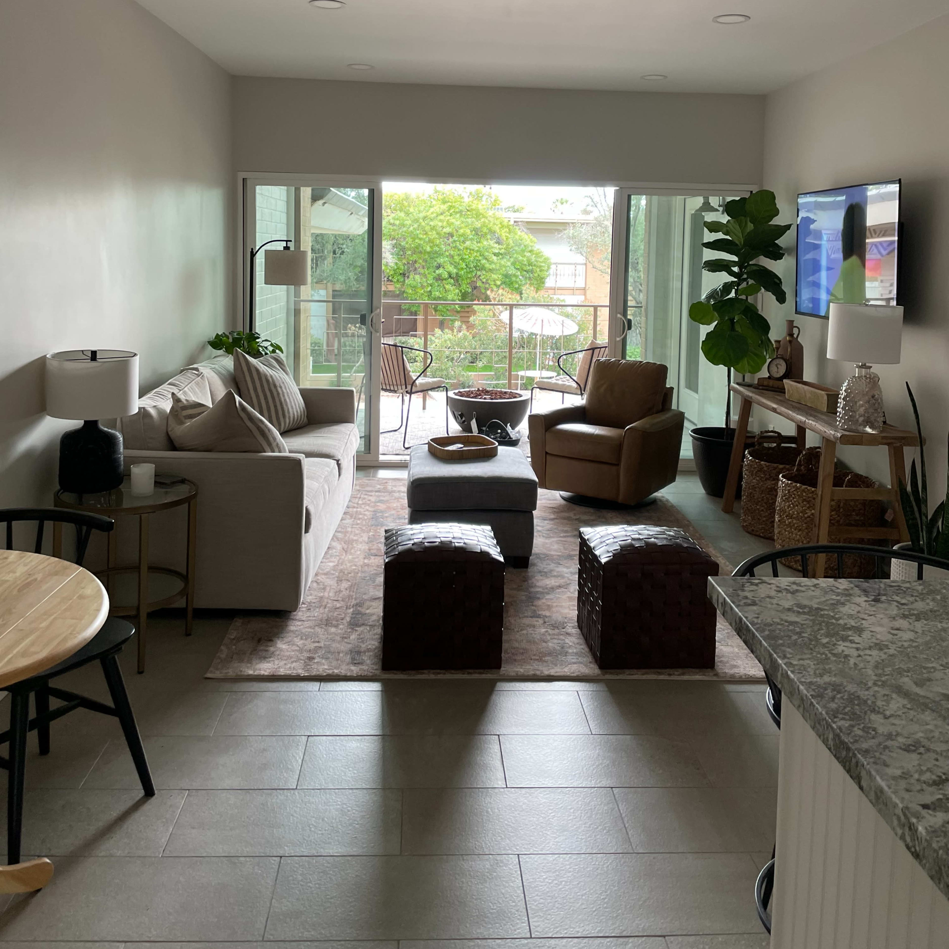 A modern living room with a sofa, a chair, a coffee table, and sliding glass doors leading to a patio area.