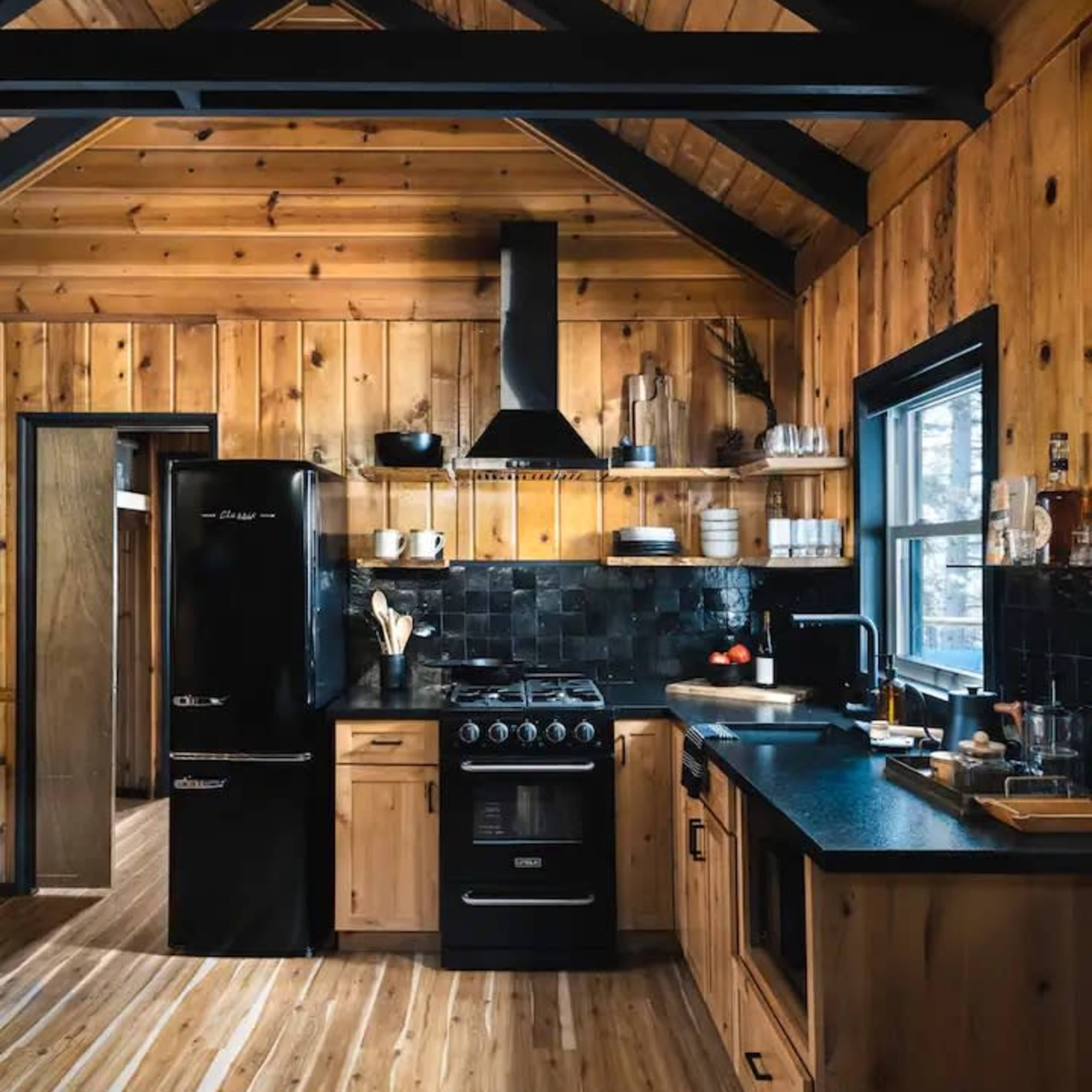 A rustic kitchen featuring wooden cabinets, a black stove, and a contrasting dark countertop.