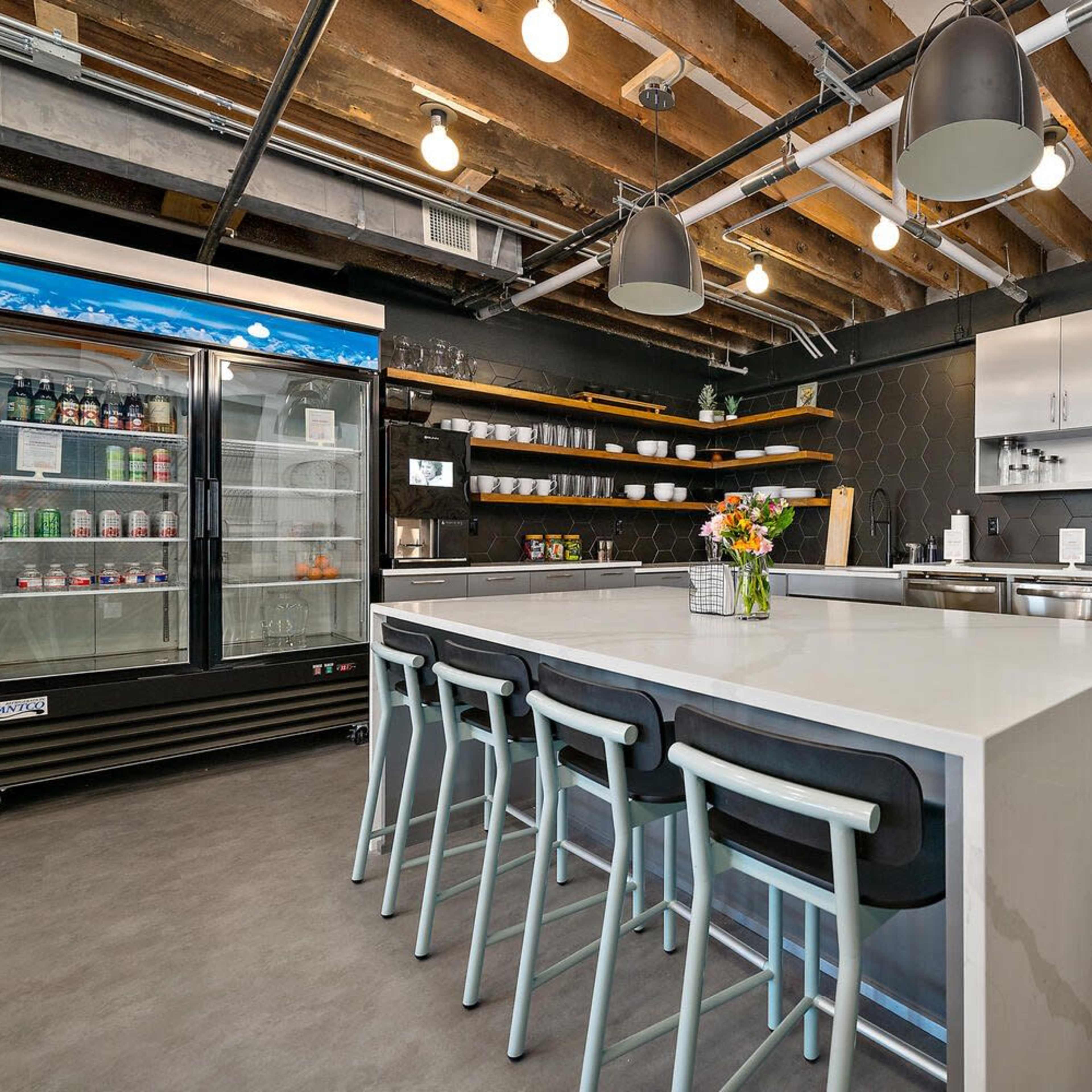 A modern kitchen with a large island, stainless steel appliances, and overhead pendant lighting.