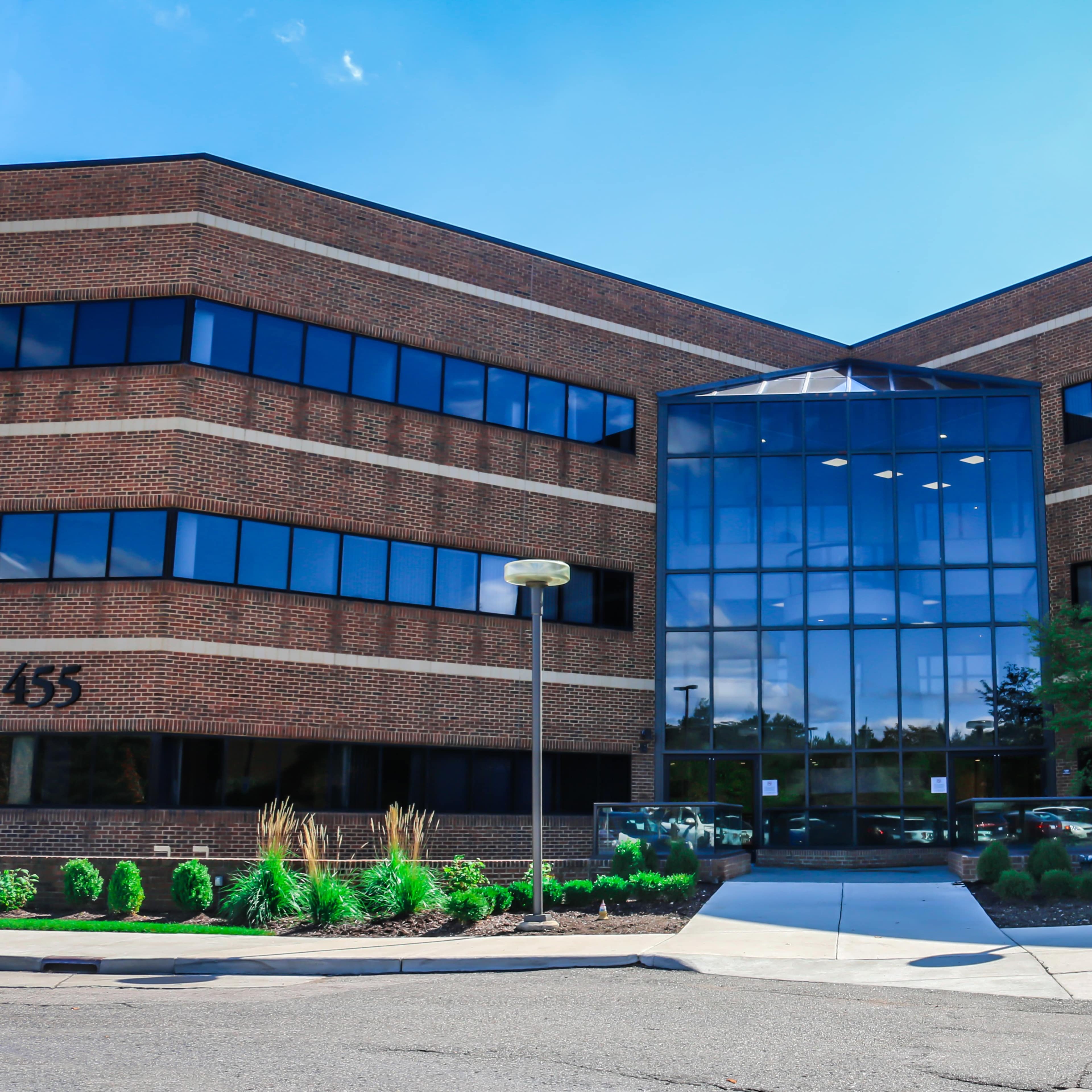A modern brick office building with large glass windows and a landscaped entrance.