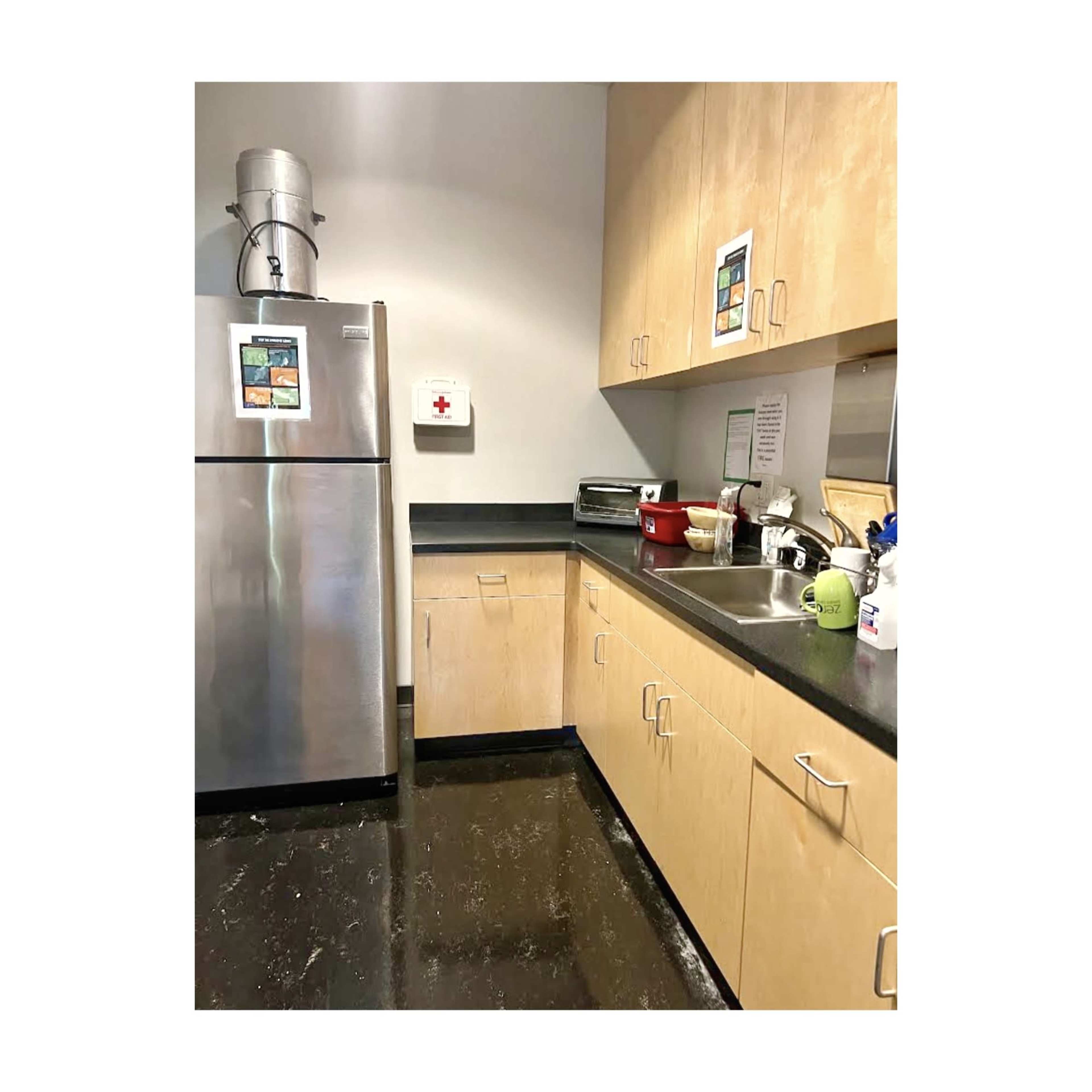 A kitchen with stainless steel appliances, wooden cabinets, and a black countertop.