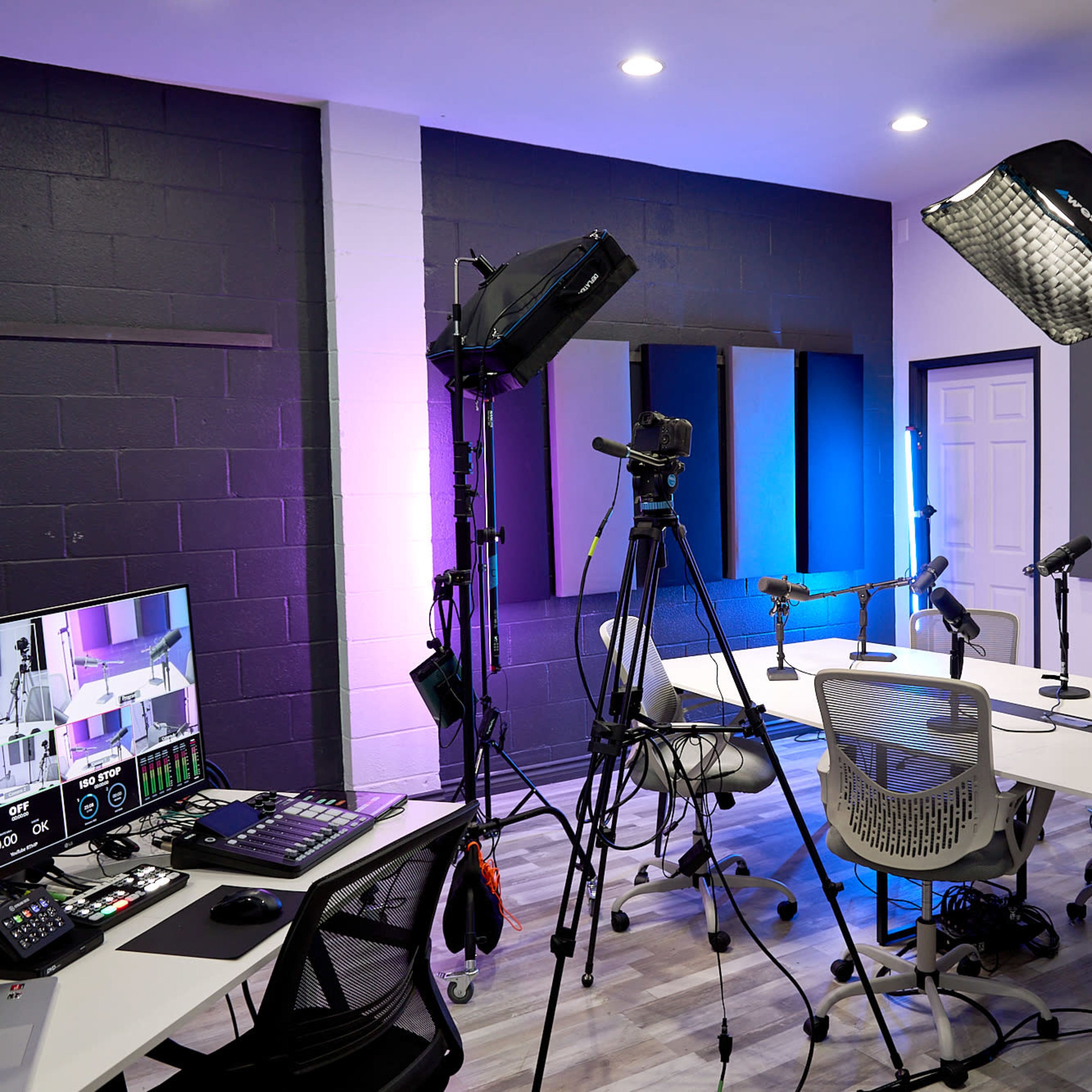 A modern studio setup featuring microphones, cameras, lighting equipment, and desks arranged for a recording session.