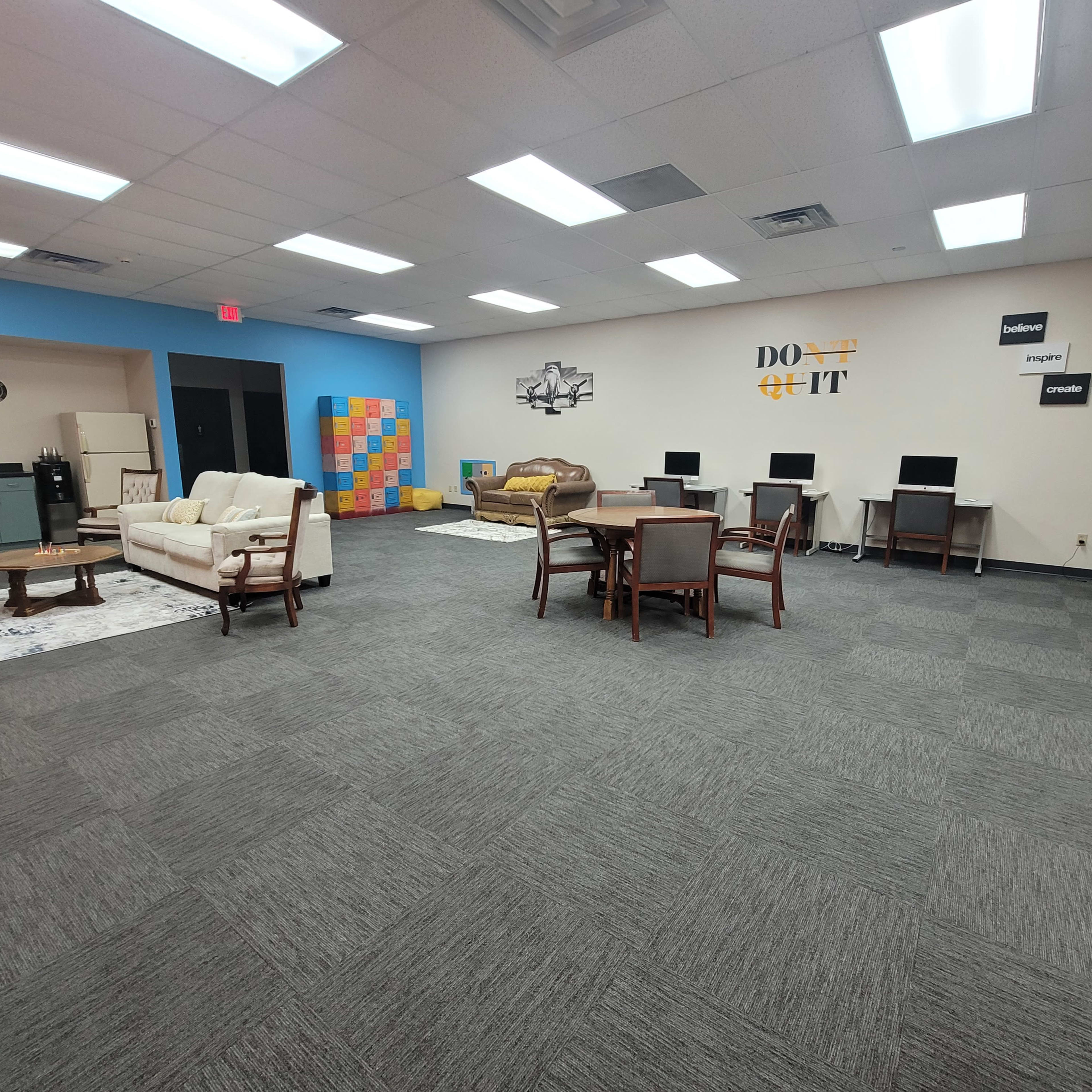 A spacious, well-lit common area featuring various seating arrangements, computer stations, and colorful wall decor.