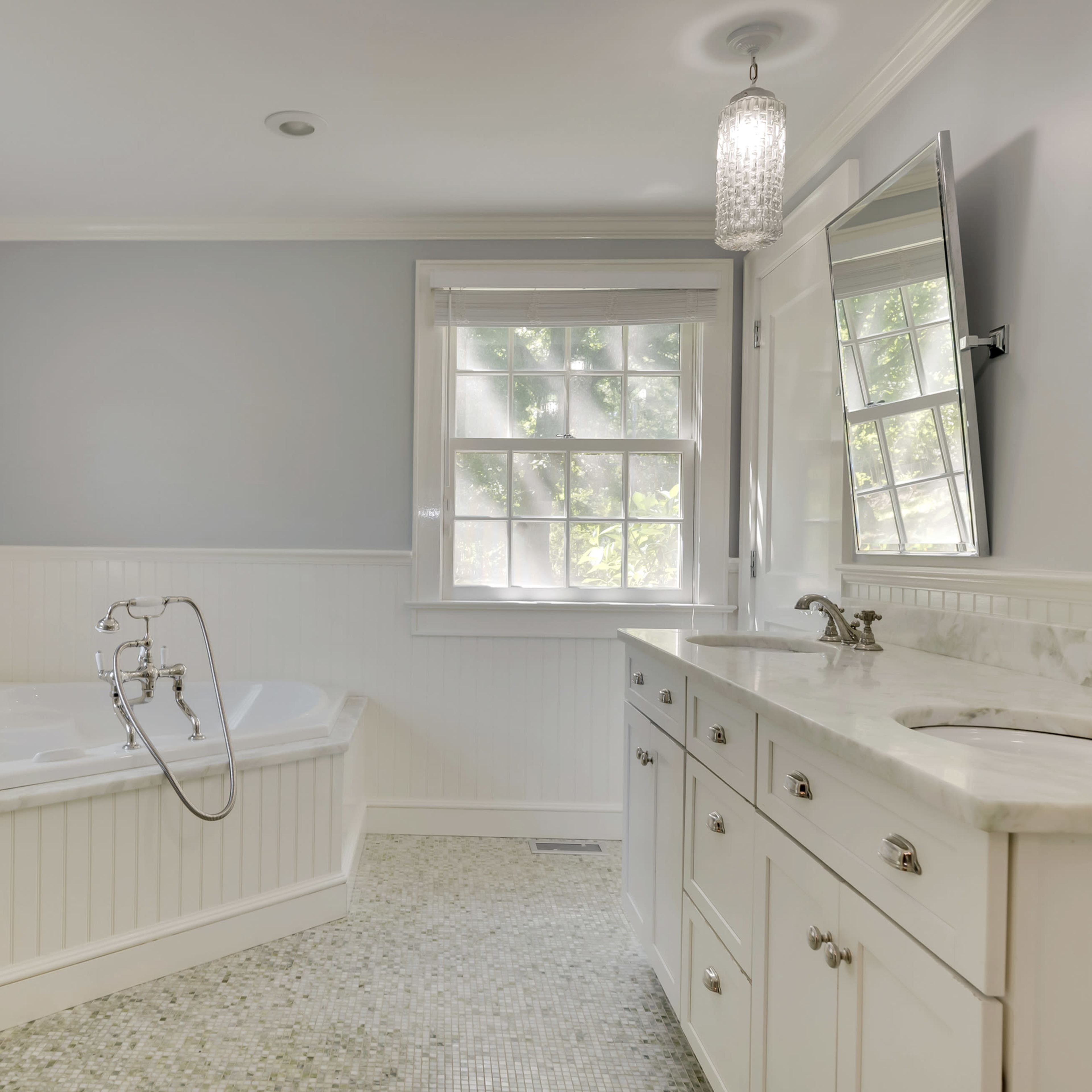 A brightly lit bathroom with a freestanding bathtub, a double sink vanity, and a window allowing natural light to enter the space.