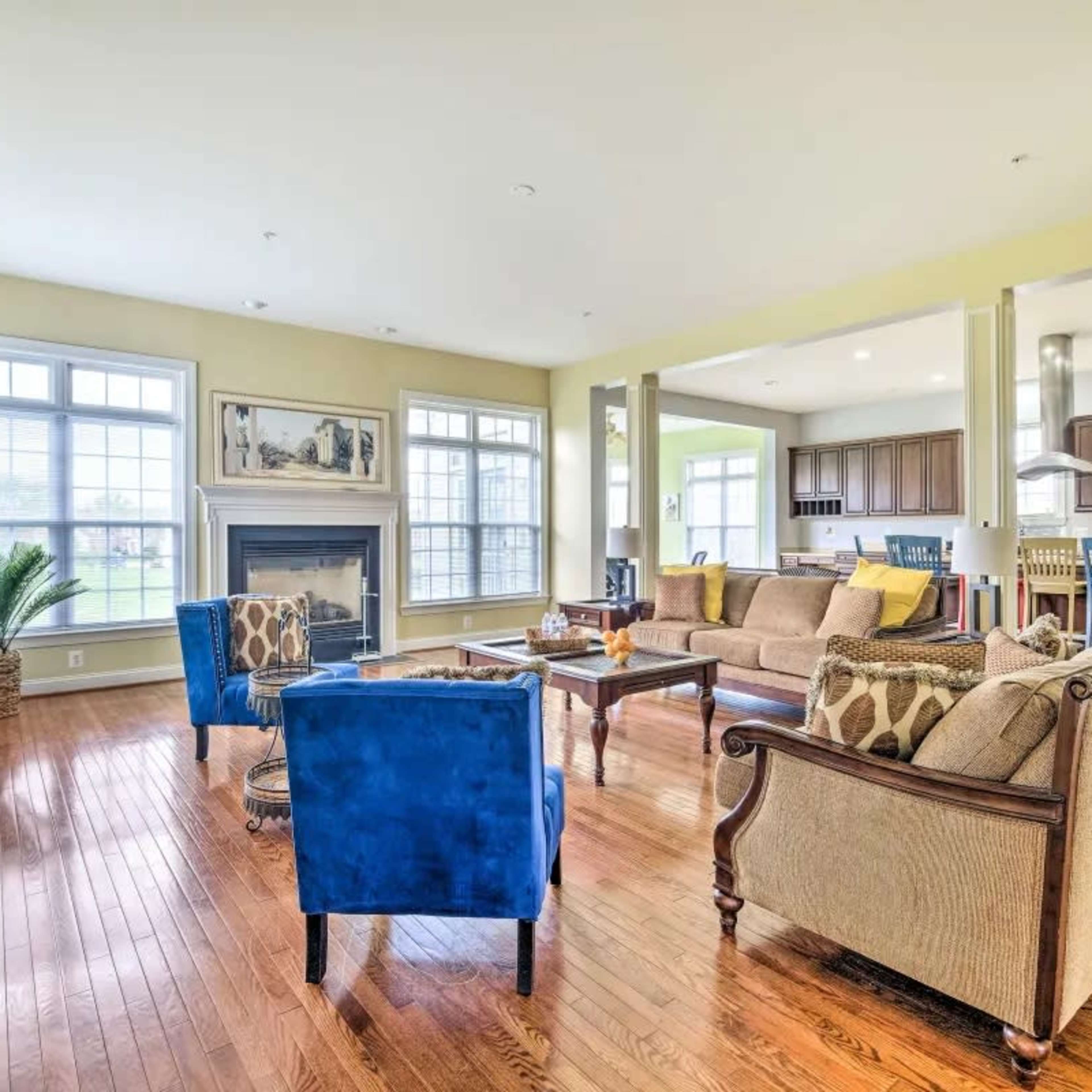 A spacious living room featuring a fireplace, a large window with natural light, and a combination of blue and tan seating arrangements.
