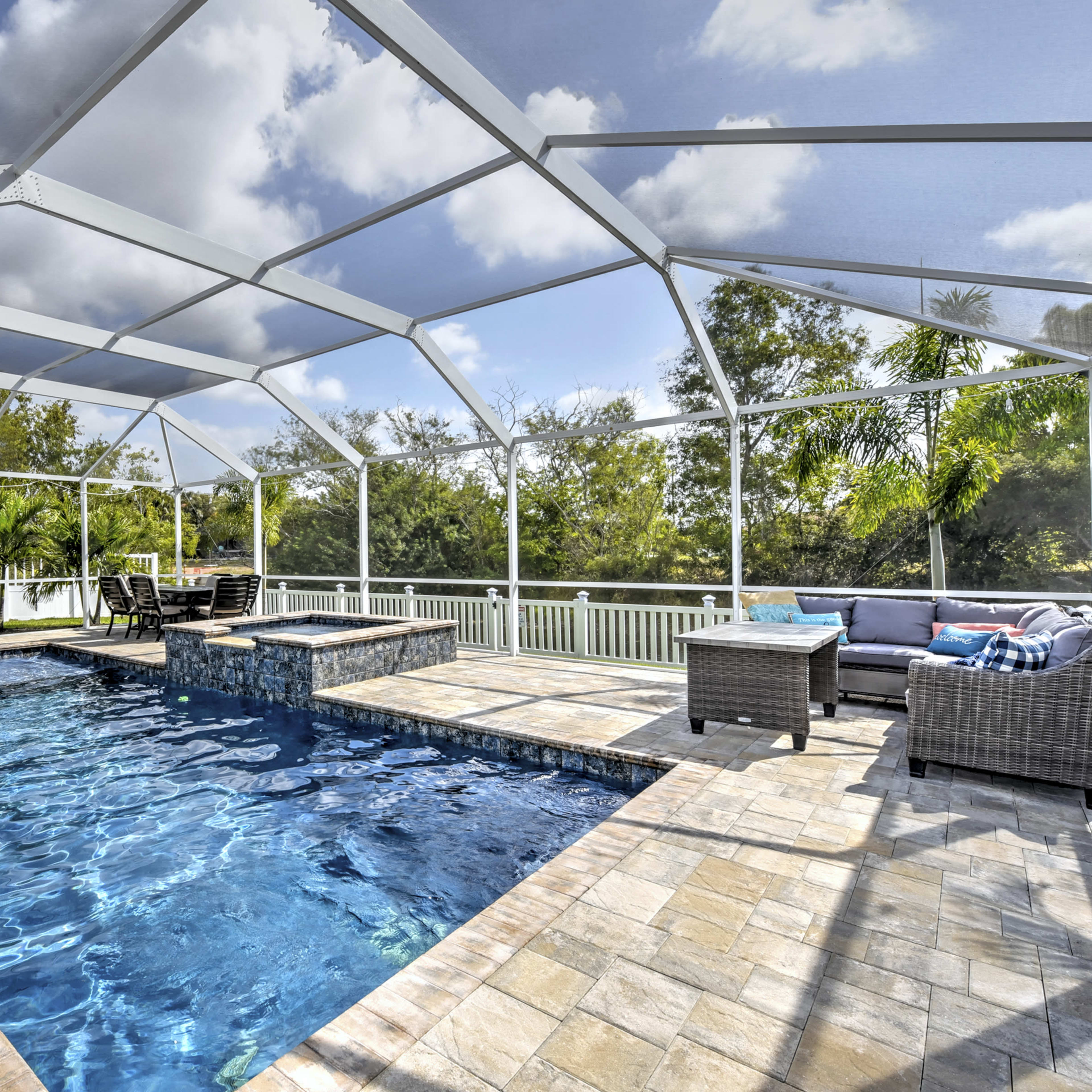 A large, open pool area with a screened enclosure, featuring a rectangular swimming pool and a patio furnished with seating.