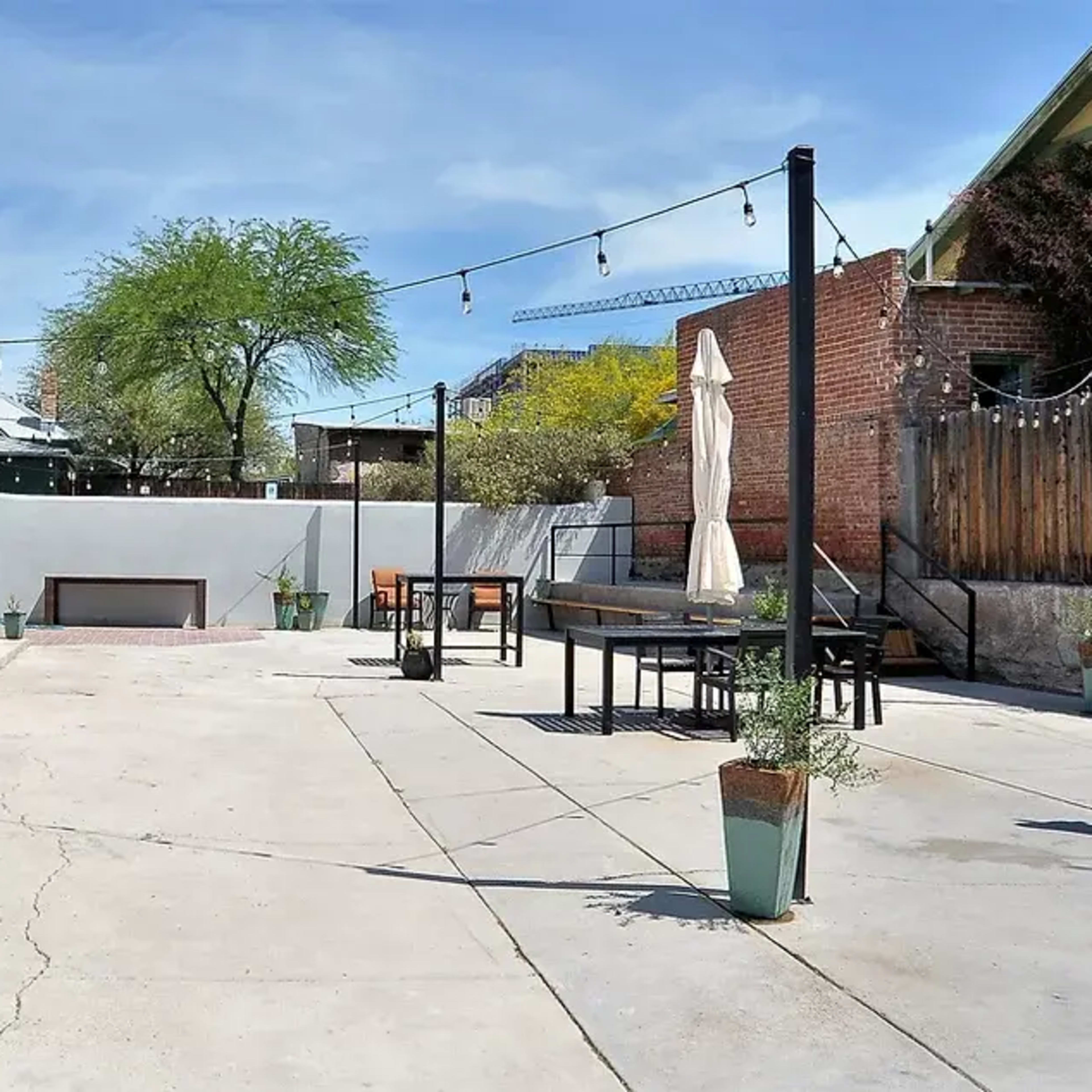 A spacious outdoor patio area with seating, planters, and string lights under a clear blue sky.