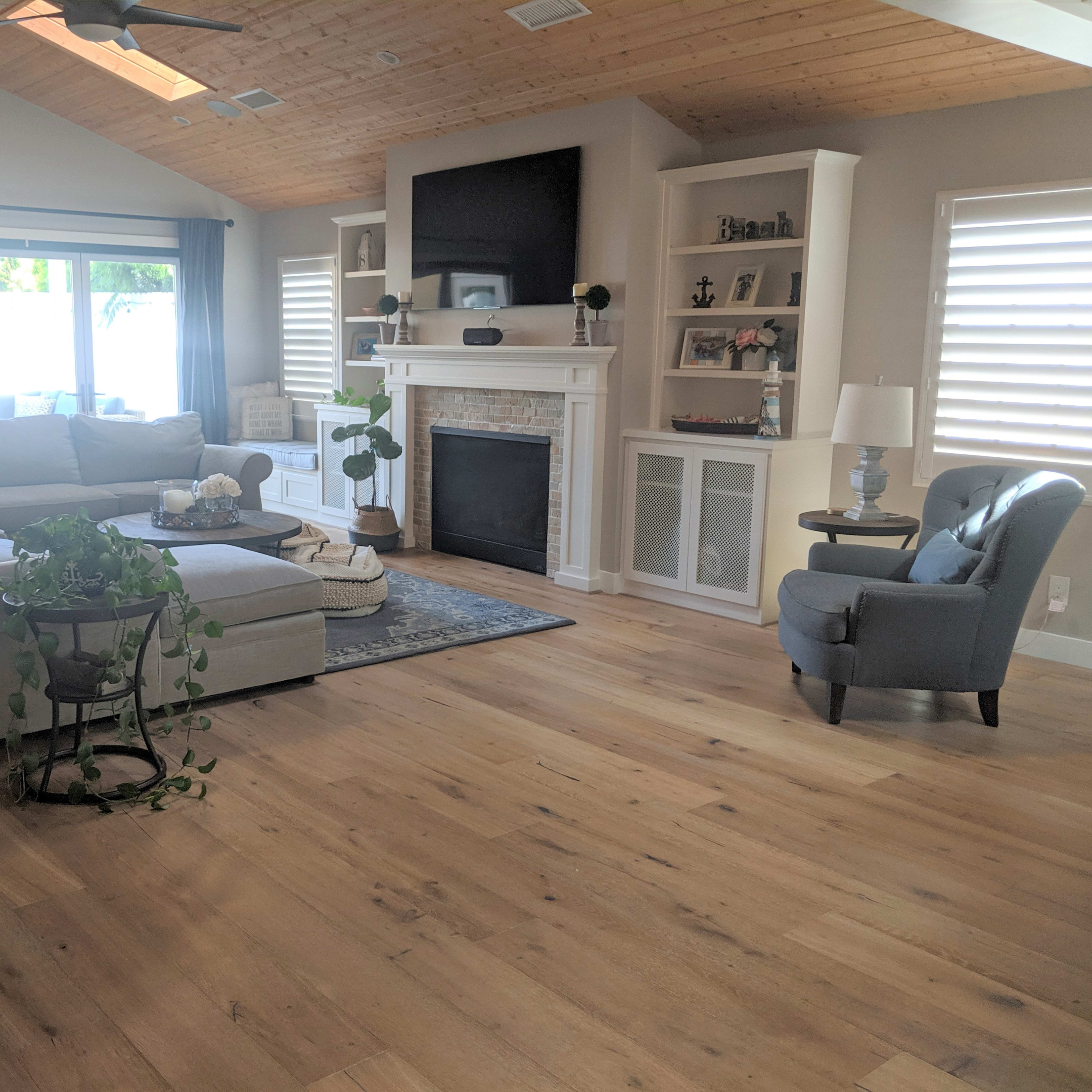 A spacious living room with a large sectional sofa, a coffee table on a rug, a fireplace, and natural light streaming through large windows.