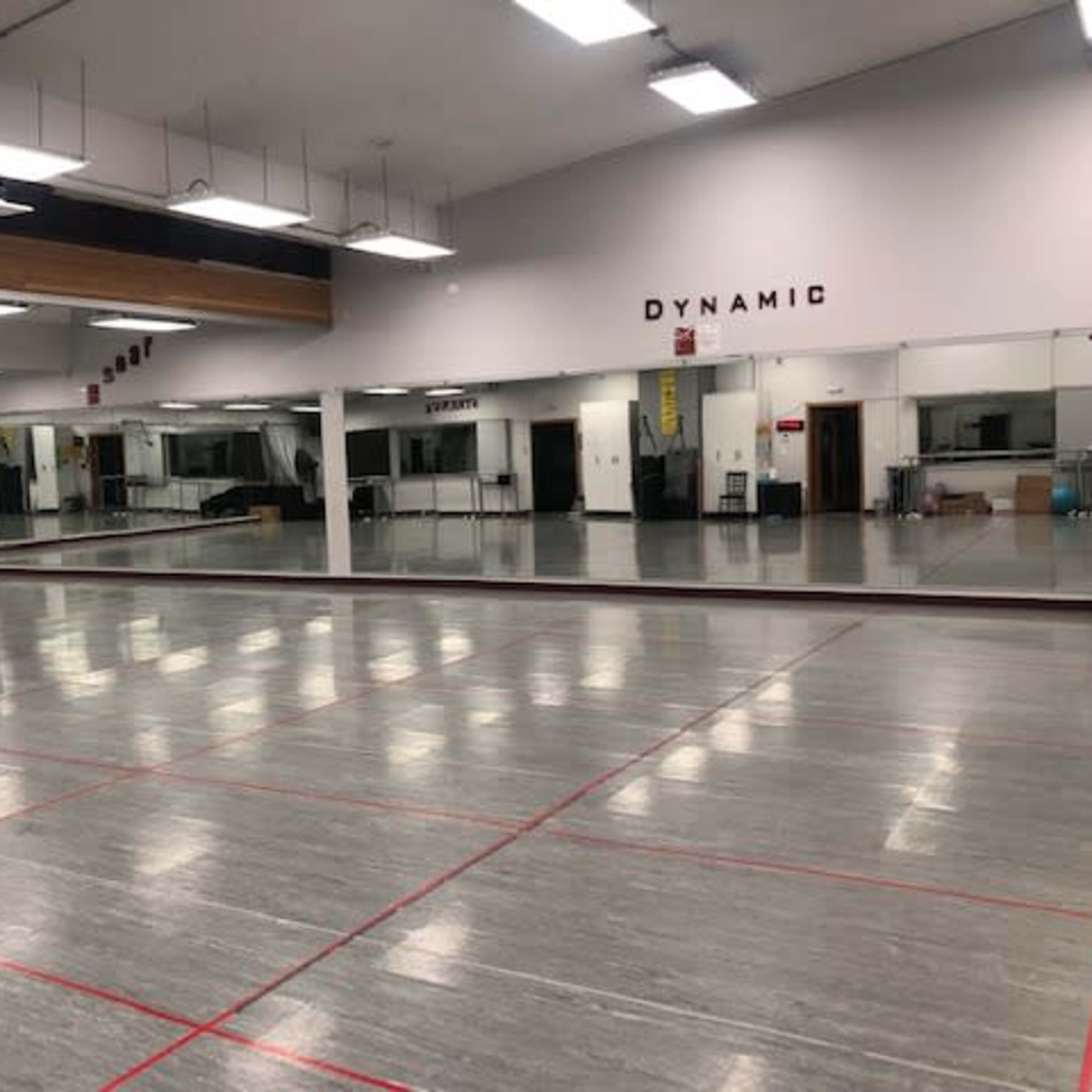 A spacious dance studio with mirrored walls and a smooth, polished floor.