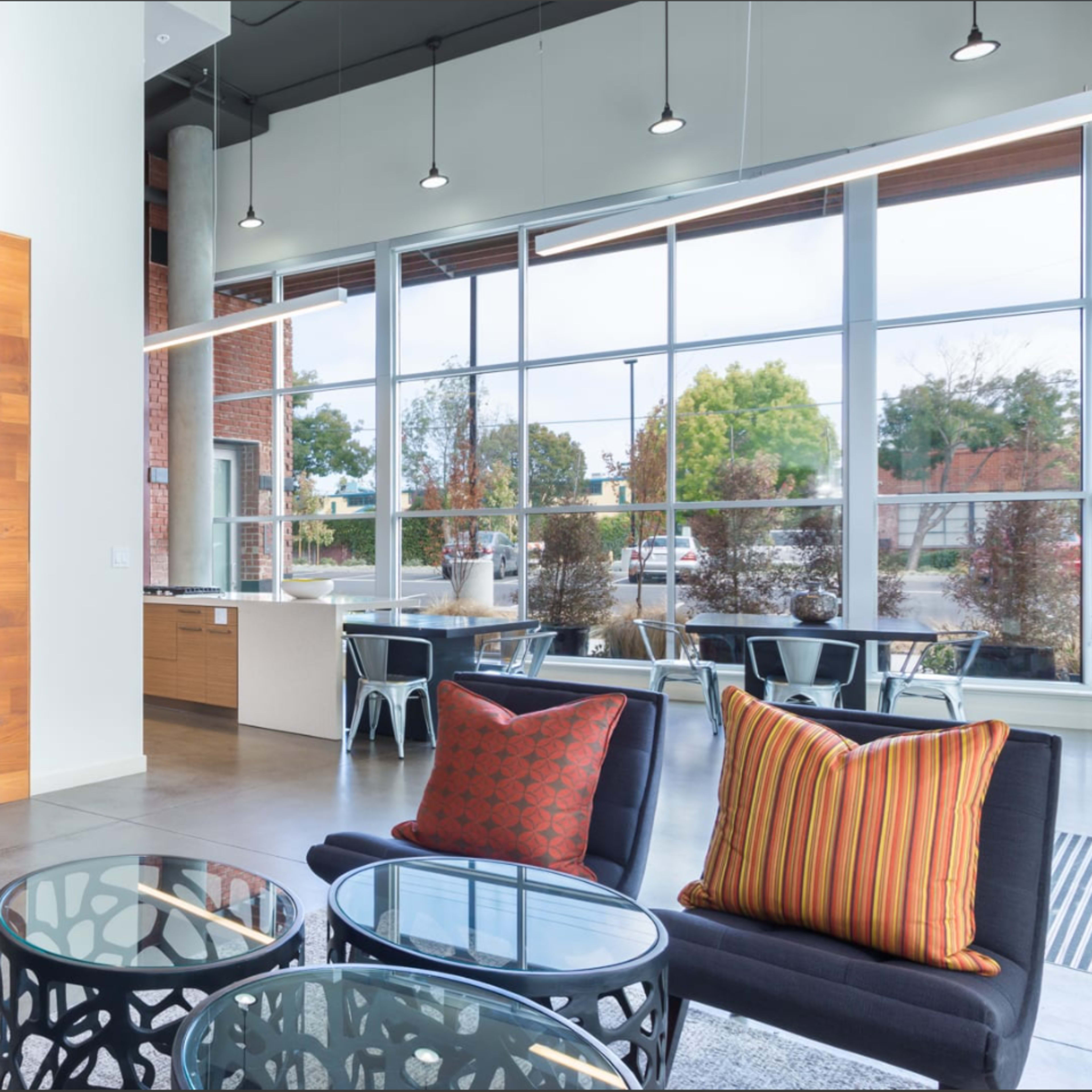 A modern lobby with seating arrangements, large windows, and decorative elements, featuring a combination of art and stylish furniture.