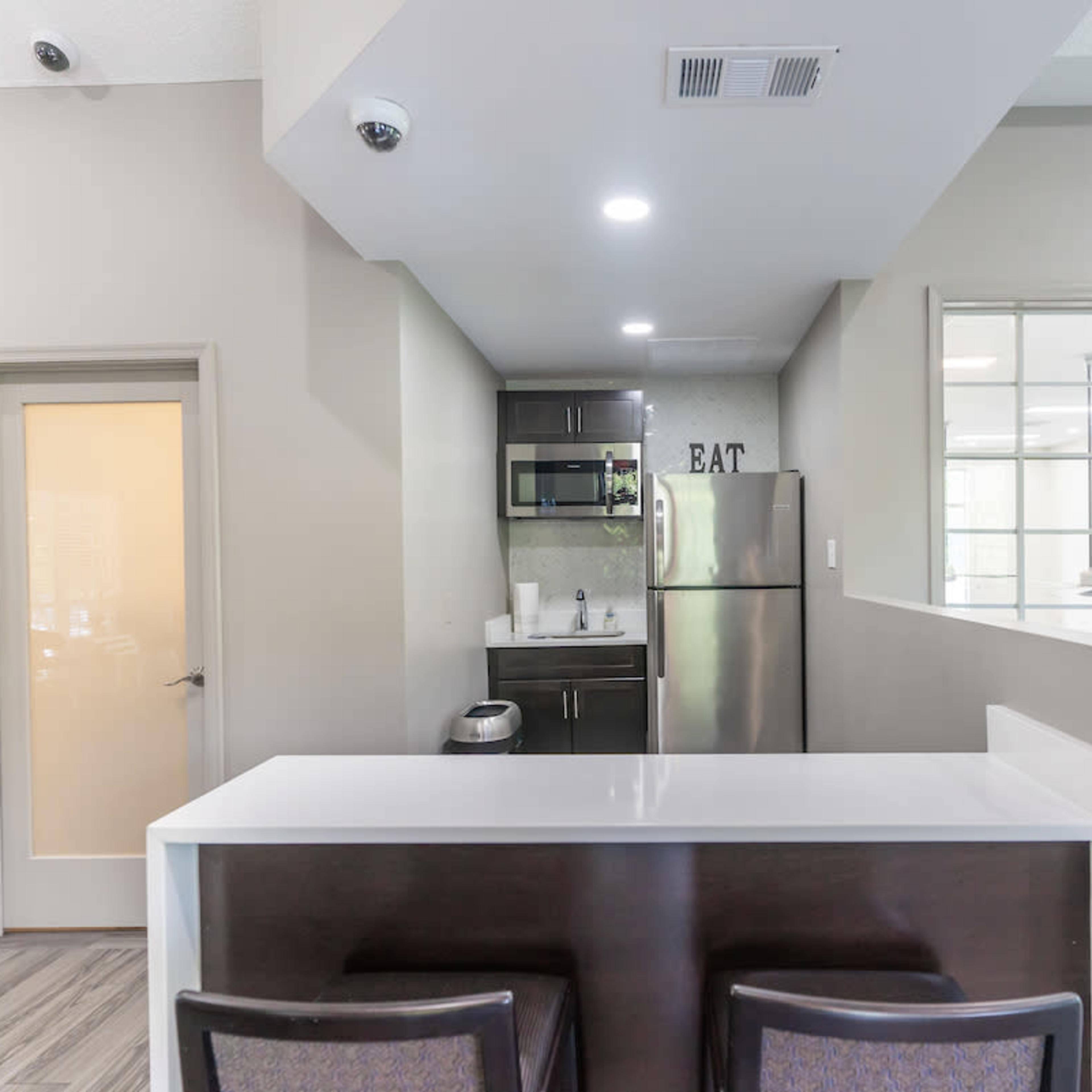 A modern kitchen features a white countertop with bar seating and stainless steel appliances.