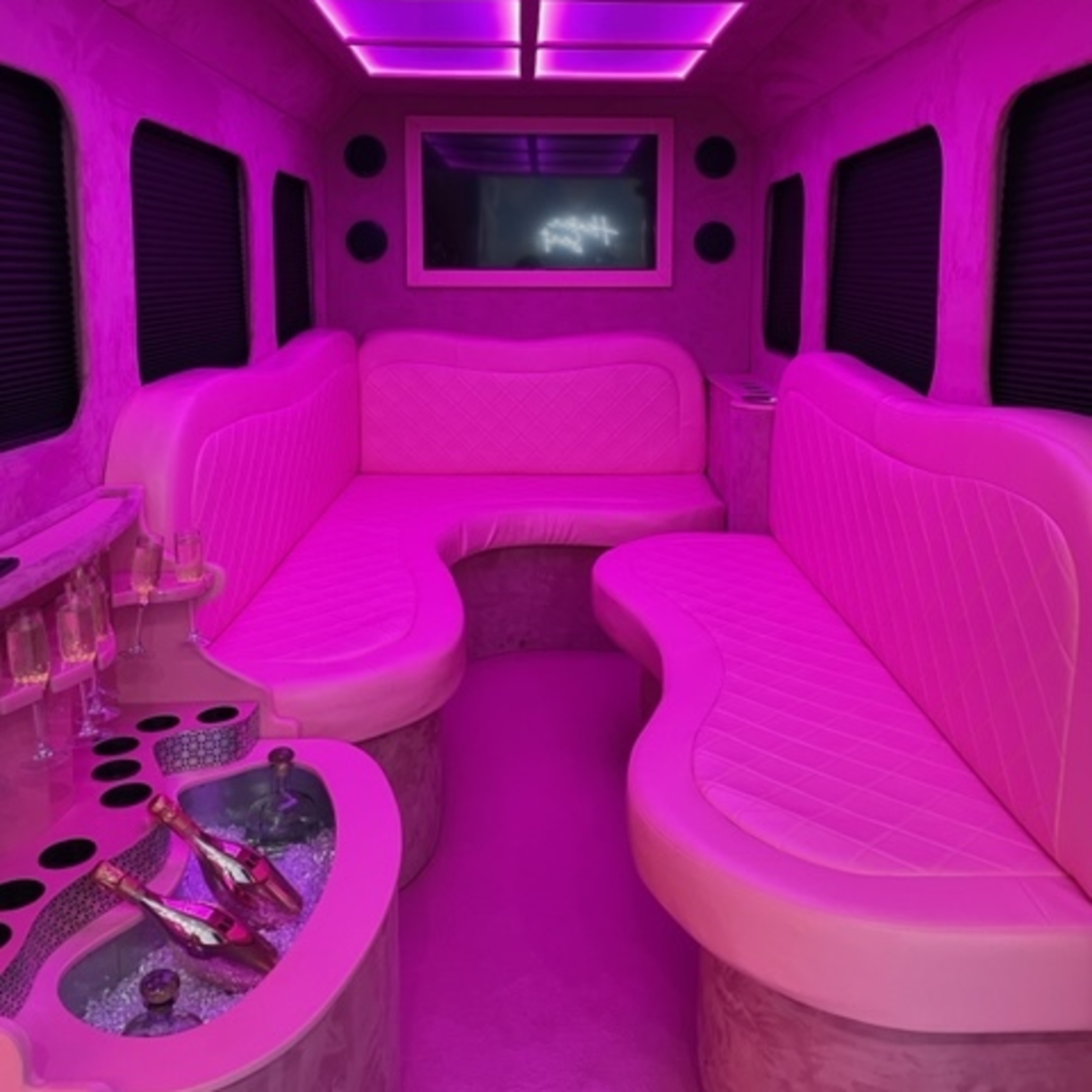 The interior of a limousine features curved seating and purple LED lighting.