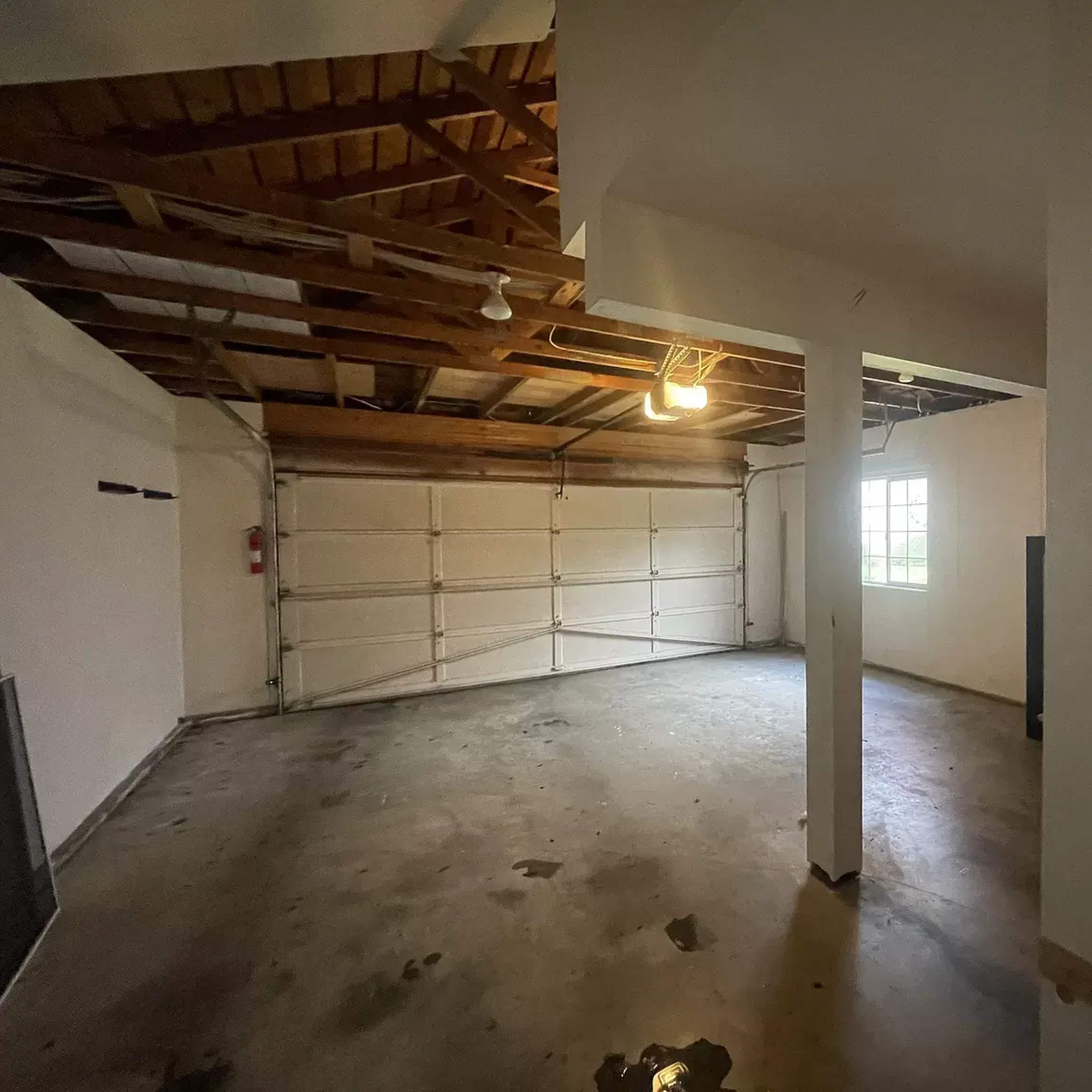 An empty garage with exposed wooden beams and a single overhead light.