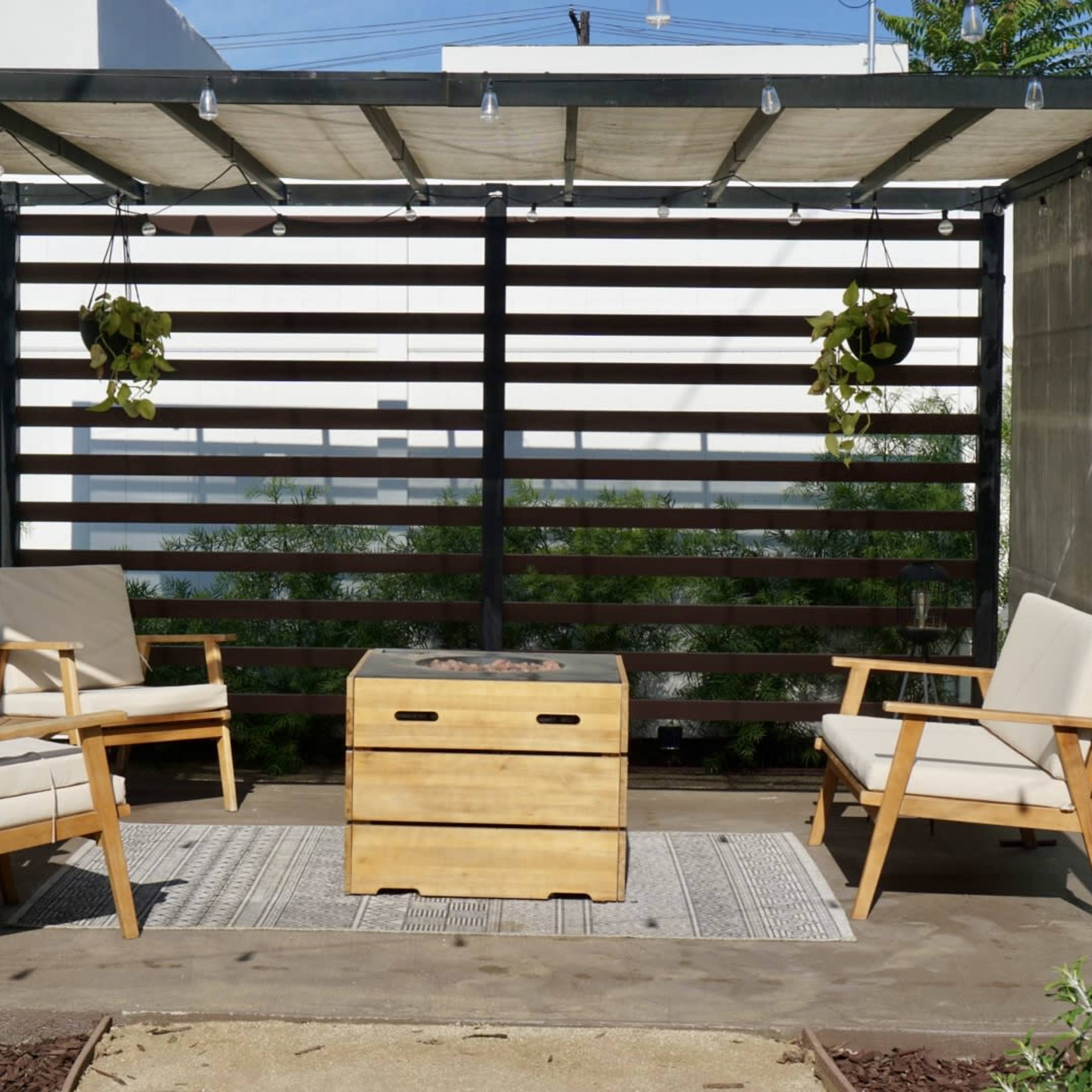 A covered outdoor seating area with two wooden chairs, a central table, and hanging plants.