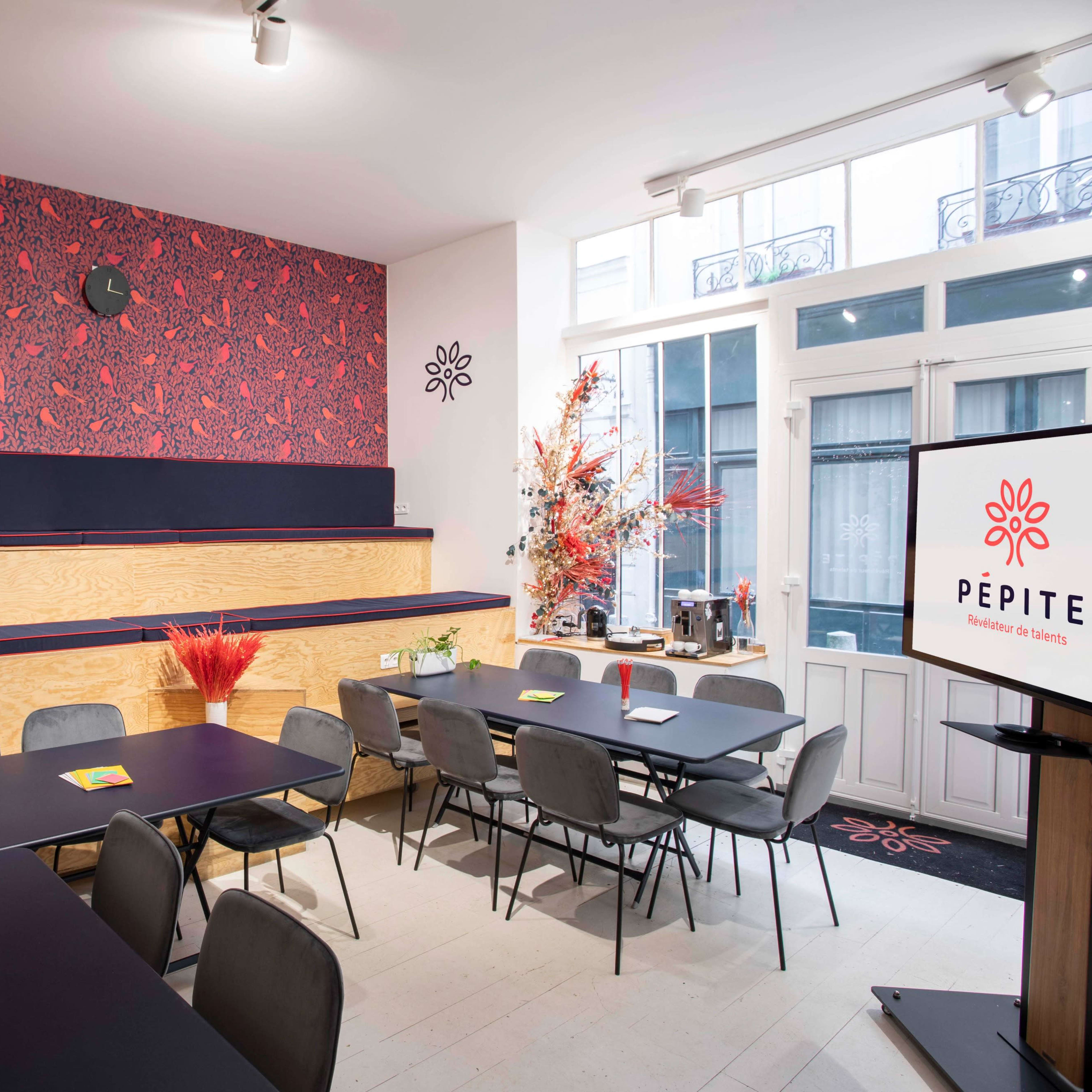 A modern meeting room with wooden and dark furniture, decorated with a patterned wallpaper and vibrant floral arrangements.