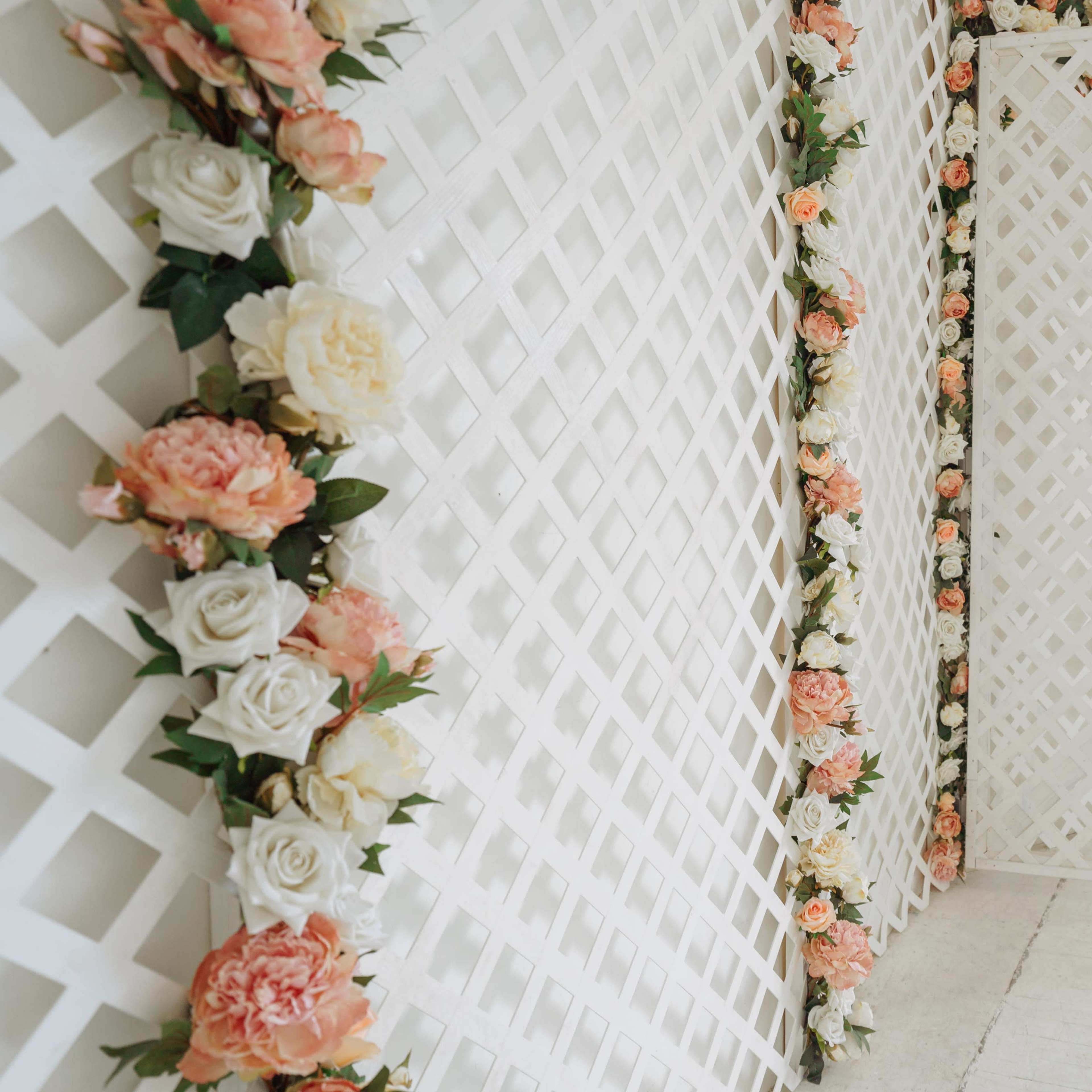A series of white lattice panels decorated with artificial flowers, arranged in a bright indoor space.