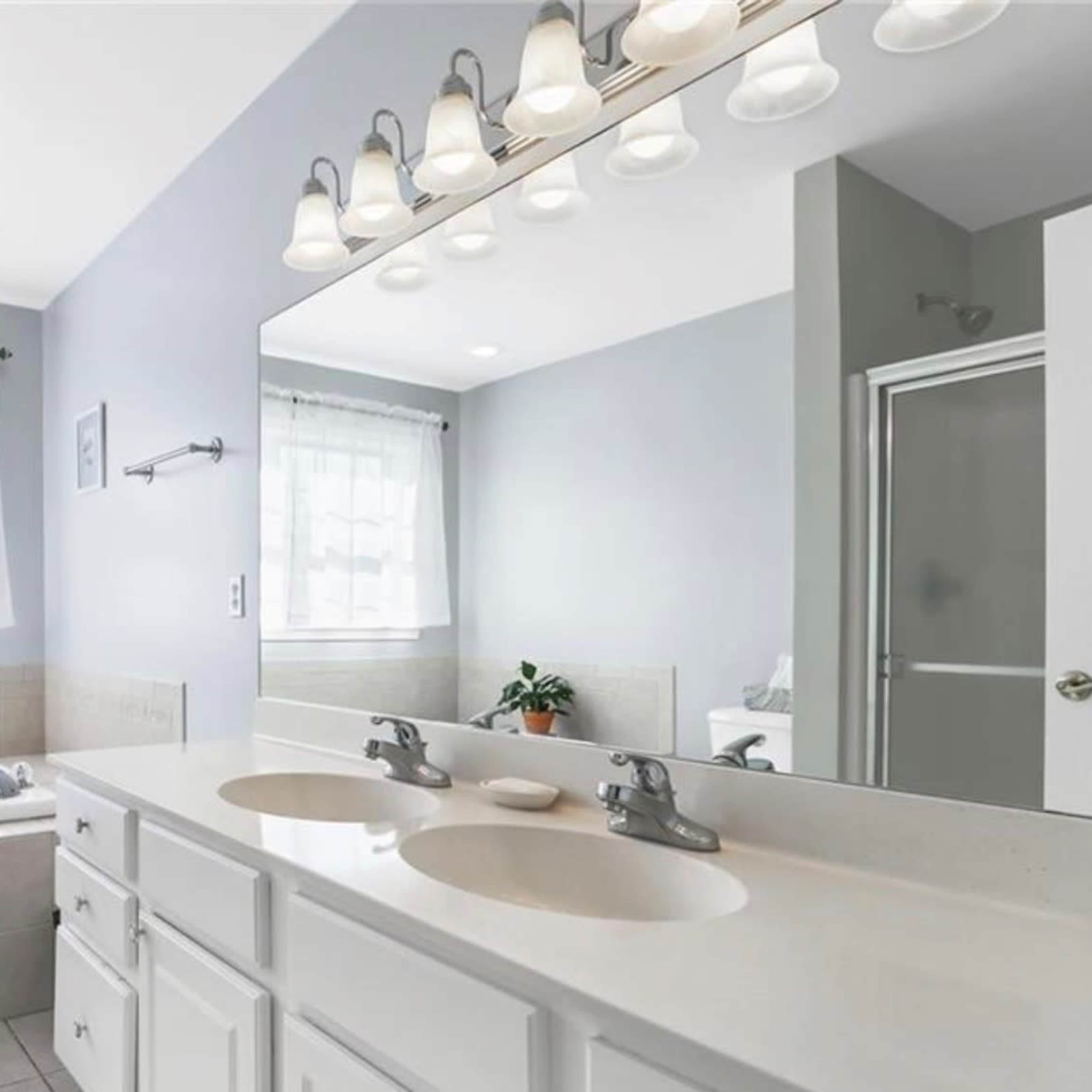 A clean bathroom features a double sink, a large mirror, a bathtub, and a shower enclosed by glass.