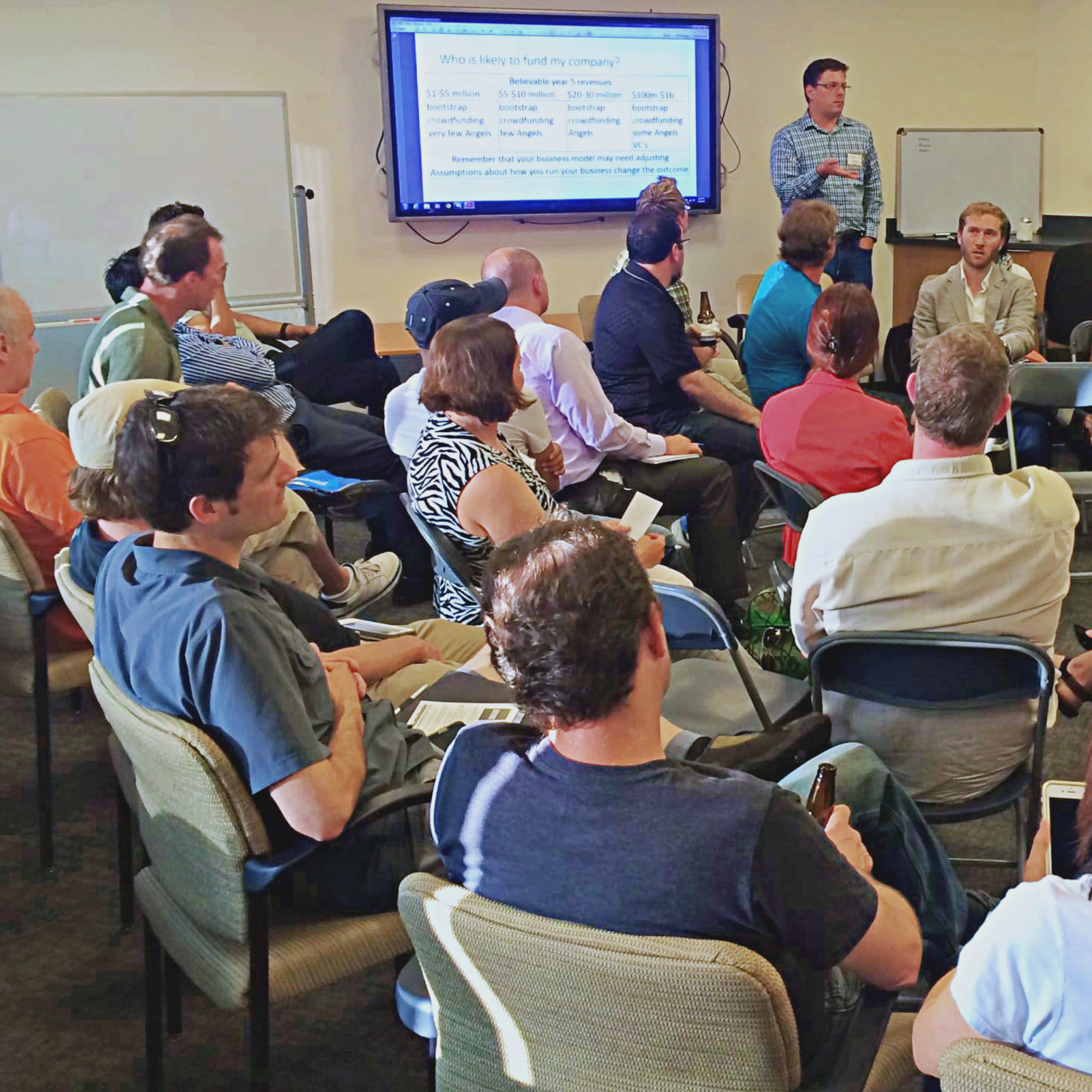 A group of people is seated in a circle attending a presentation in a conference room.