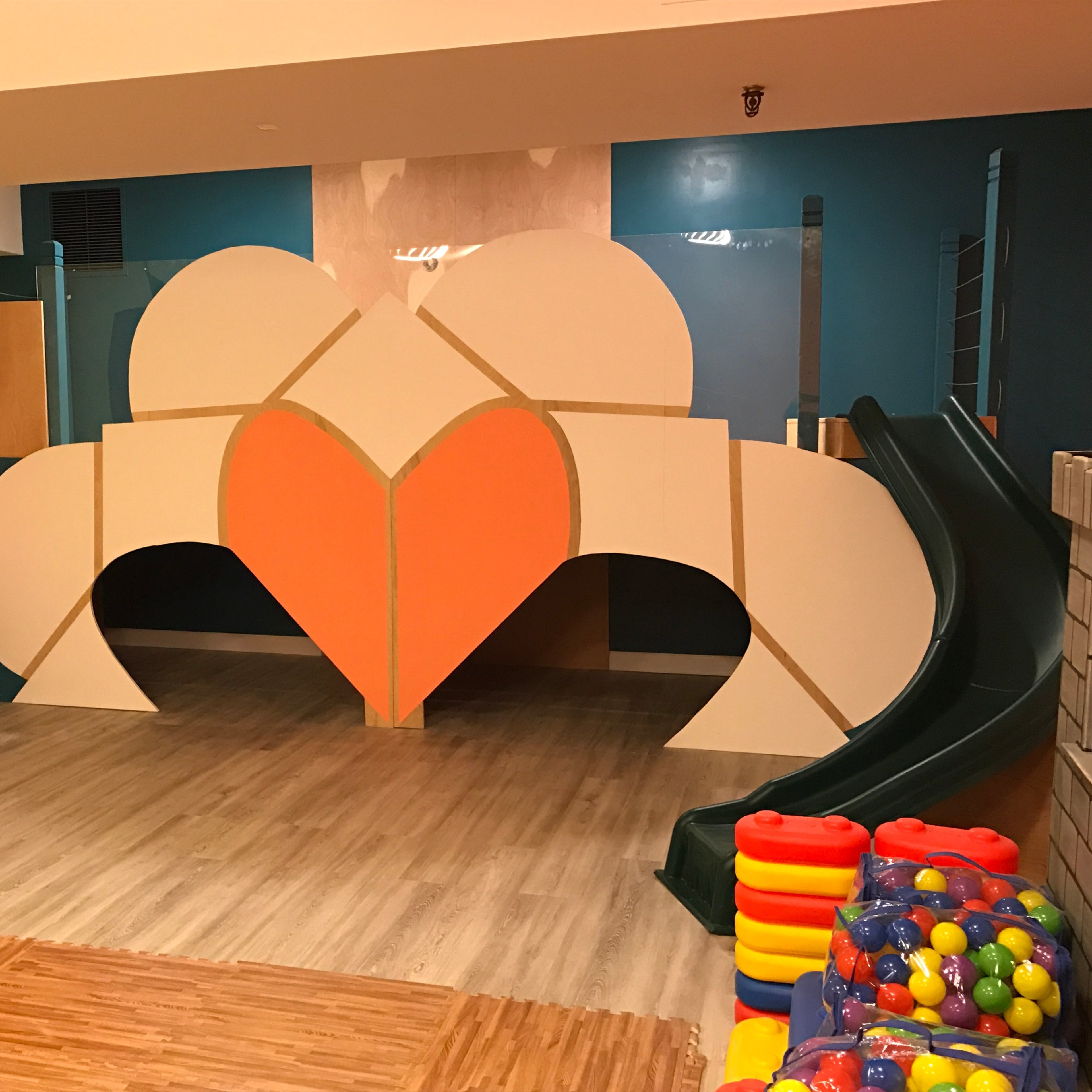 A children's play area featuring a large, colorful climbing structure with a slide, stairs, and various toy blocks.