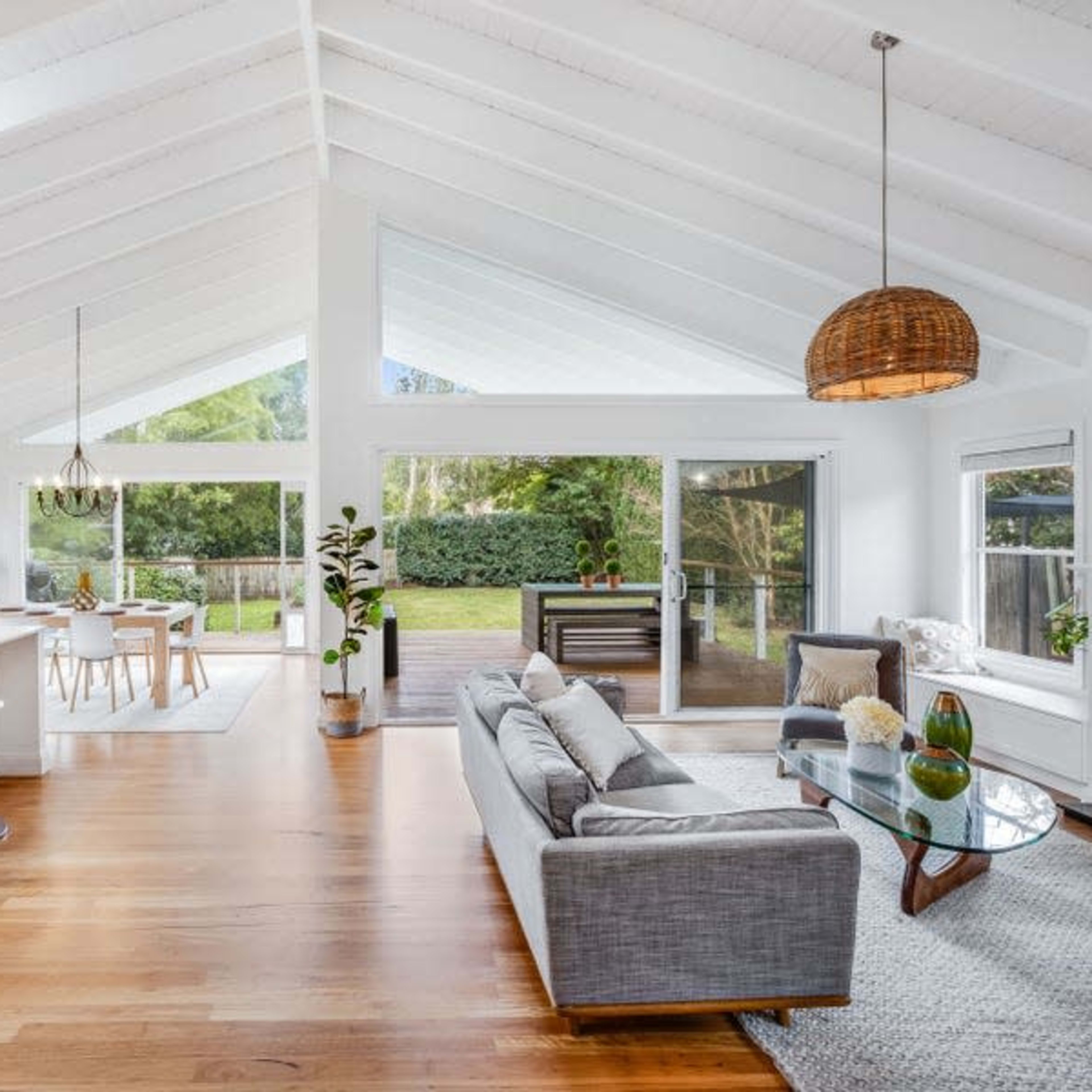 A spacious, open-concept living area features high ceilings, a modern kitchen with bar stools, and large windows that let in natural light.