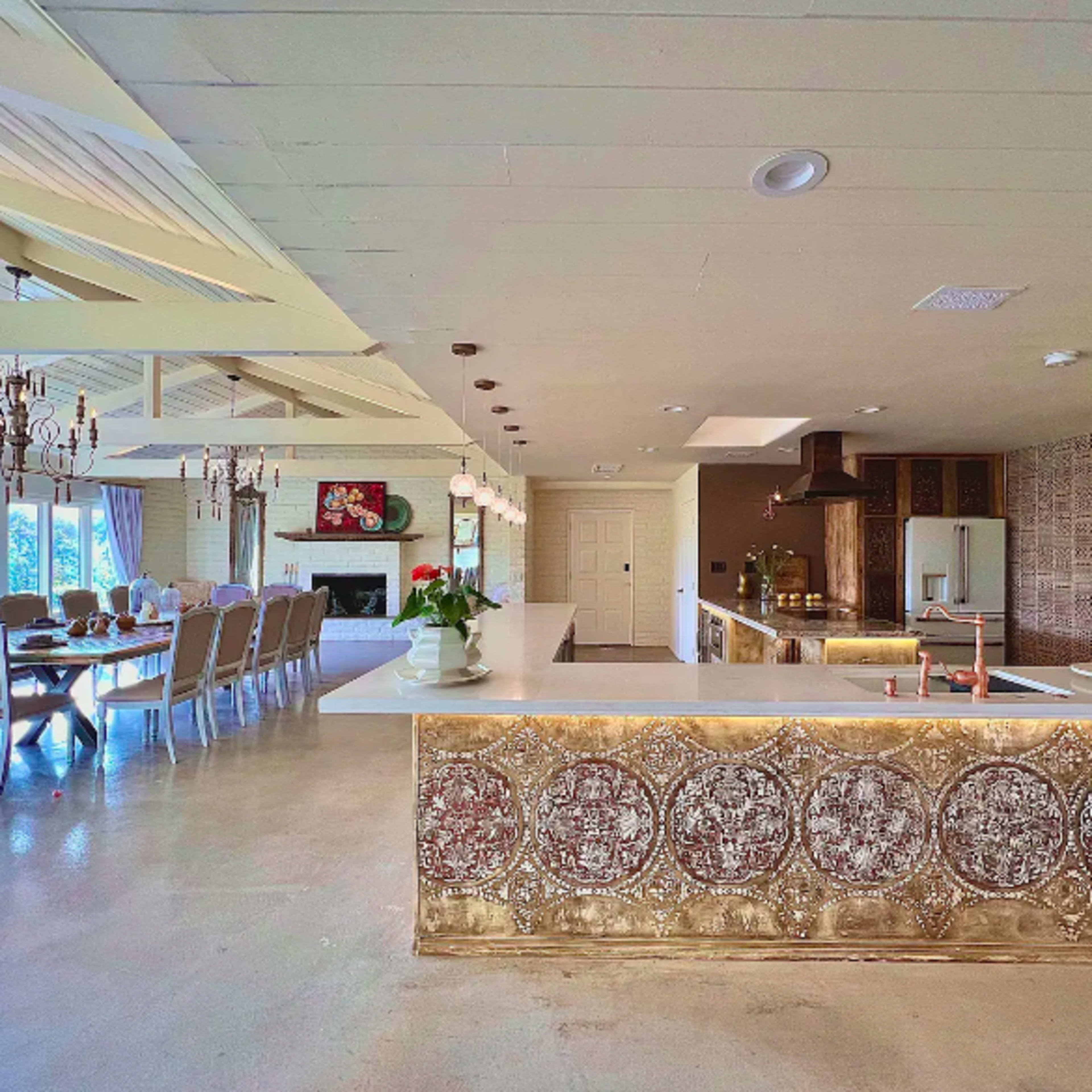 A spacious kitchen and dining area featuring a large island with a decorative panel, surrounded by a dining table and chairs.