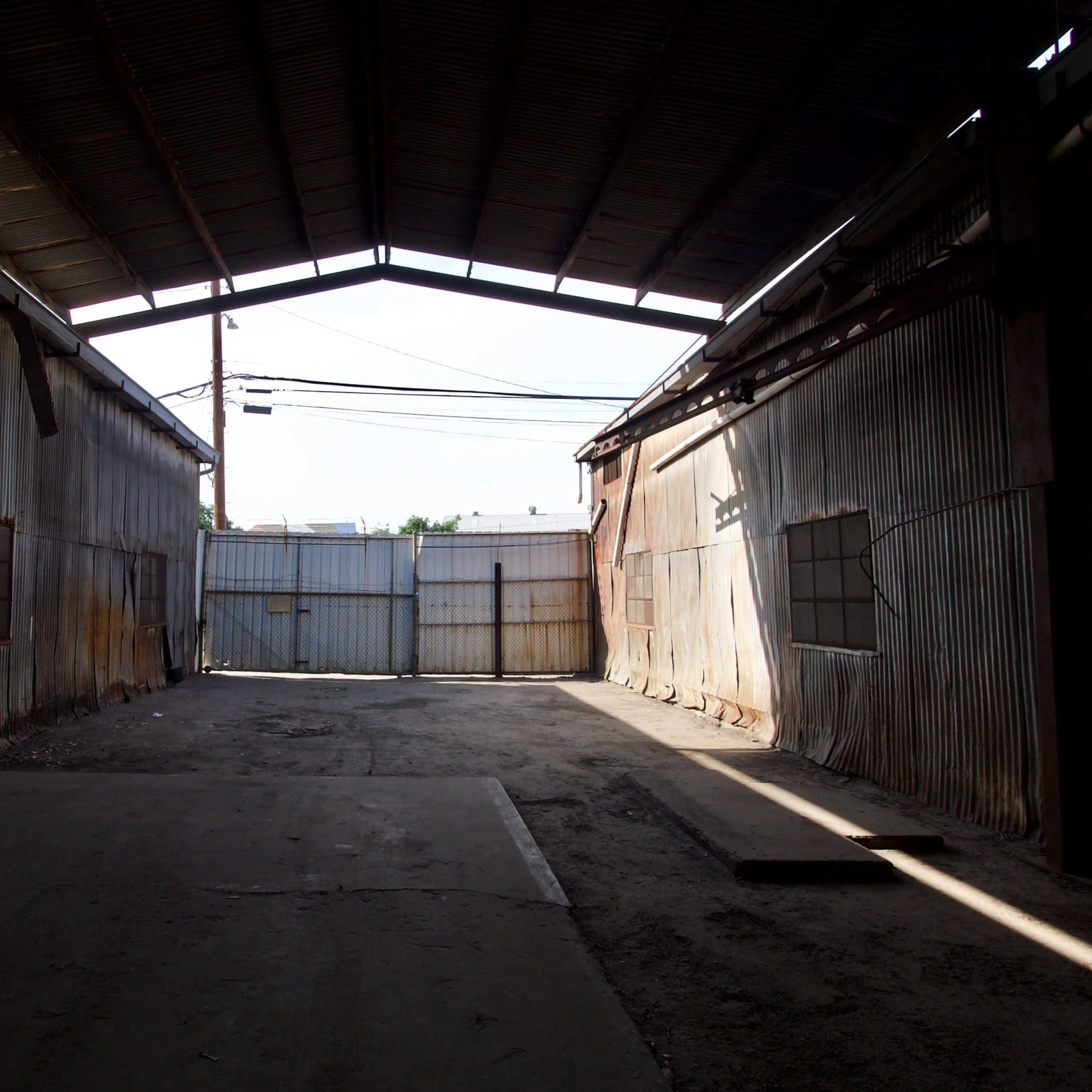 The interior of a large, empty warehouse with metal walls and a high ceiling.