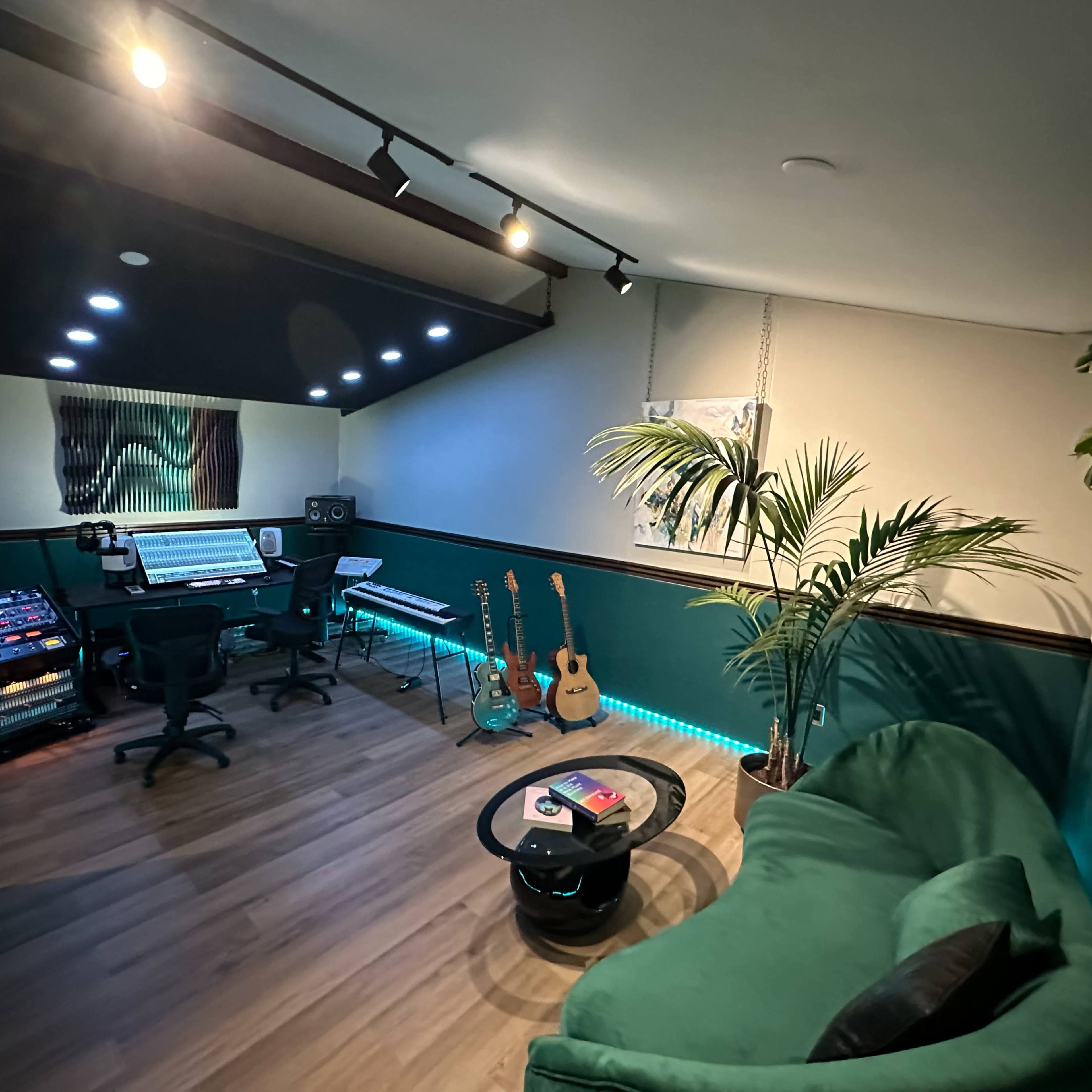 A modern music studio featuring a control desk, musical instruments, and a cozy seating area illuminated with LED lights.