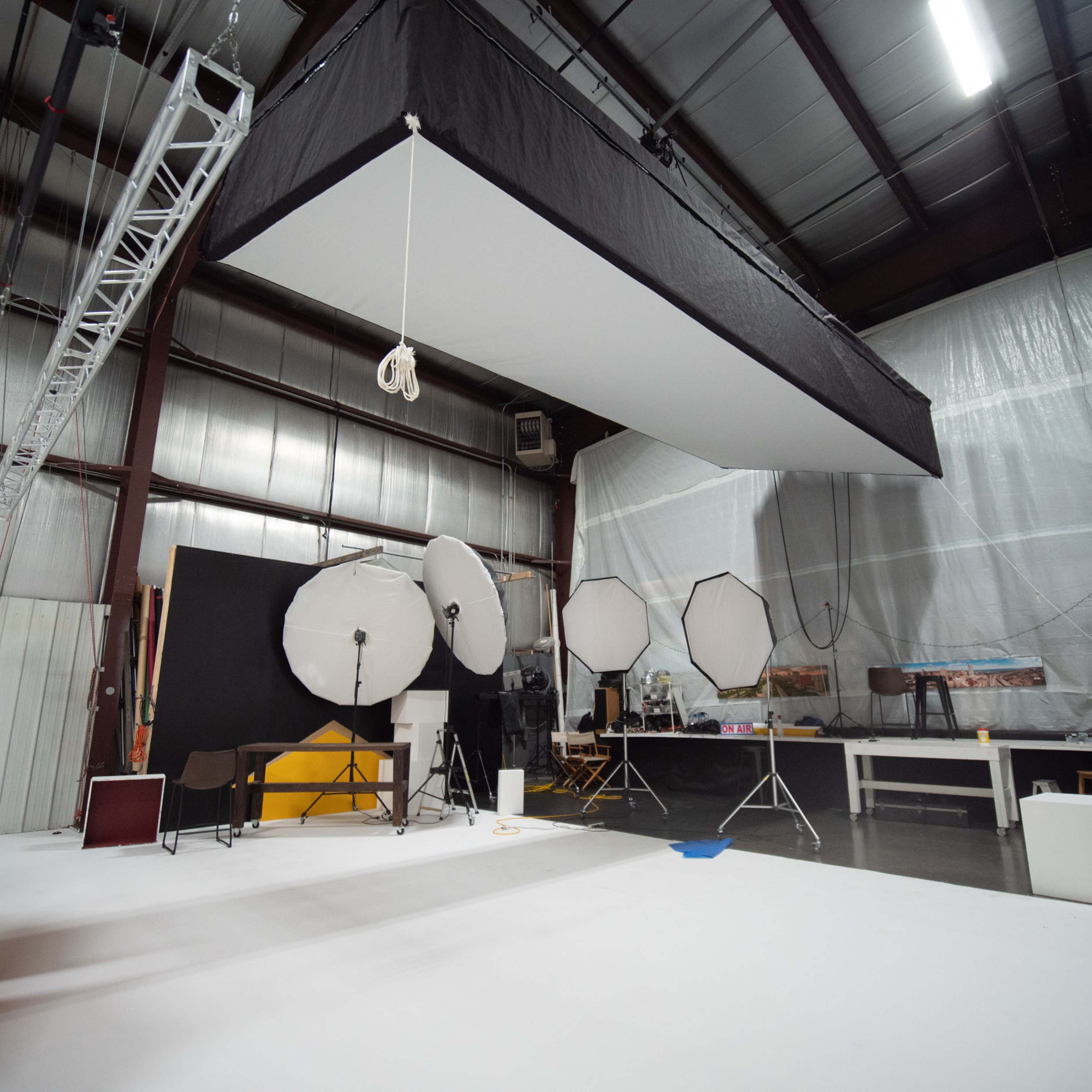 A photography studio equipped with several large softbox lights, a white backdrop, and various pieces of studio equipment.