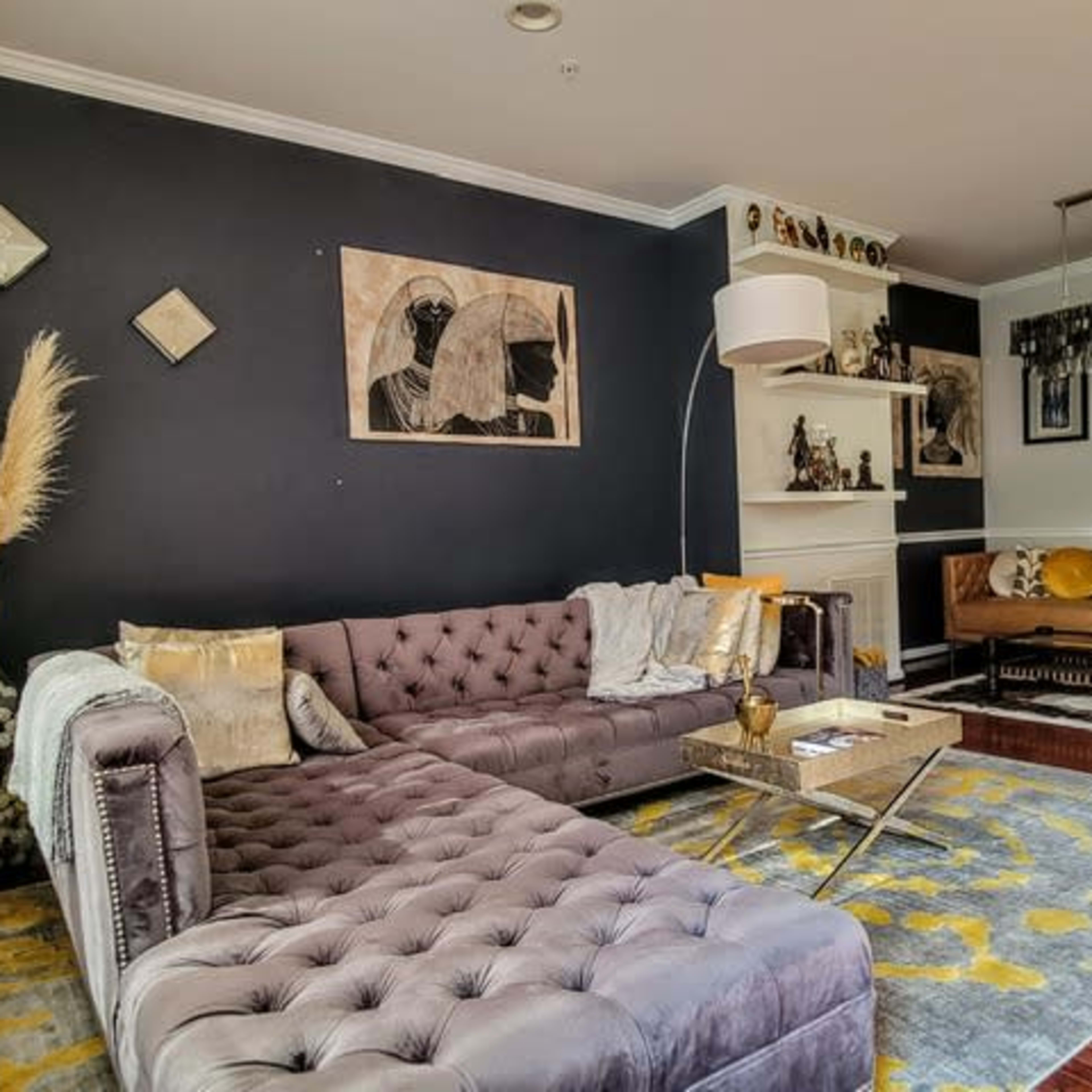 A stylish living room featuring a dark accent wall, two sofas, a coffee table, and various decorative items, all arranged to create a cozy atmosphere.