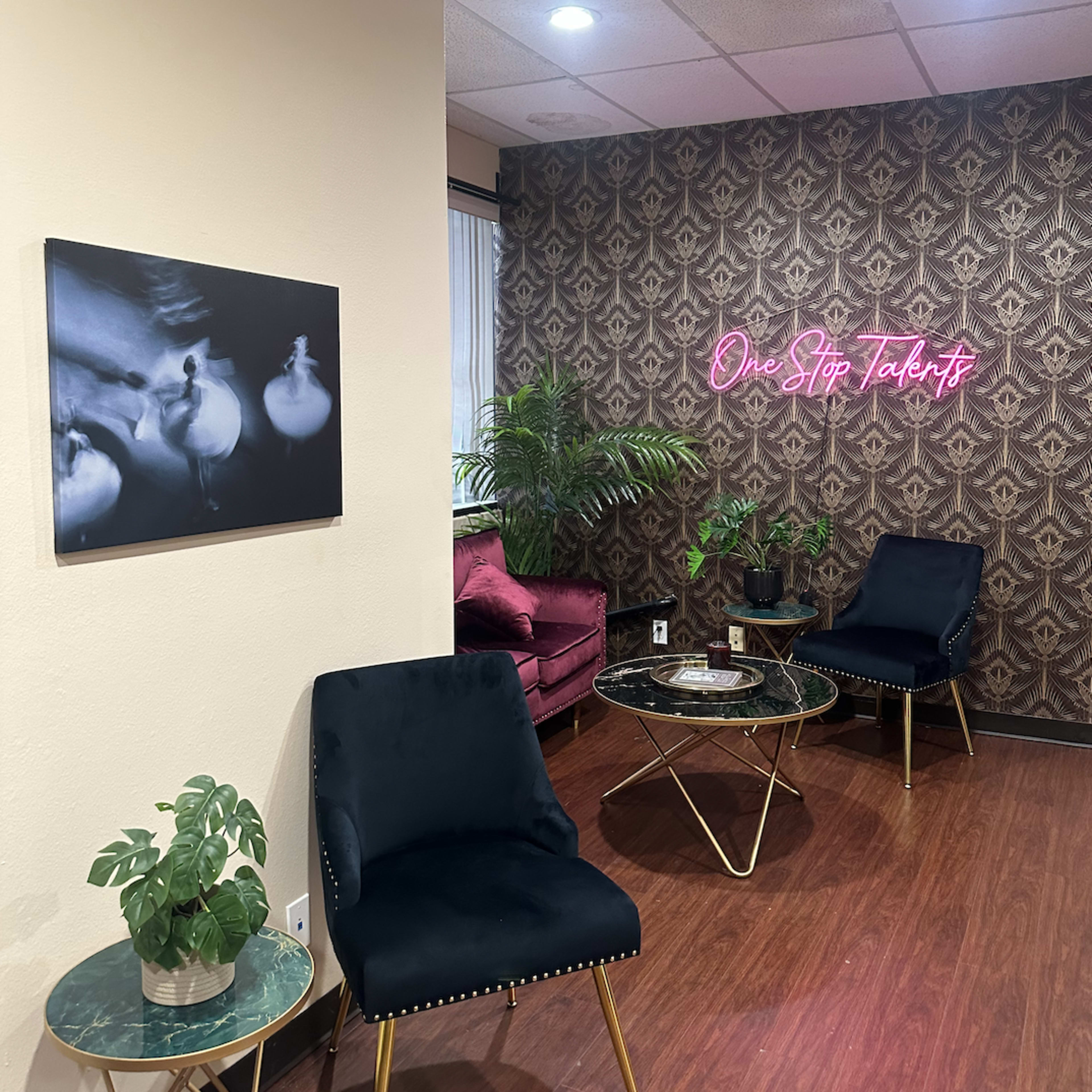 A modern interior with dark chairs, a small plant, and neon signage against a patterned wall.