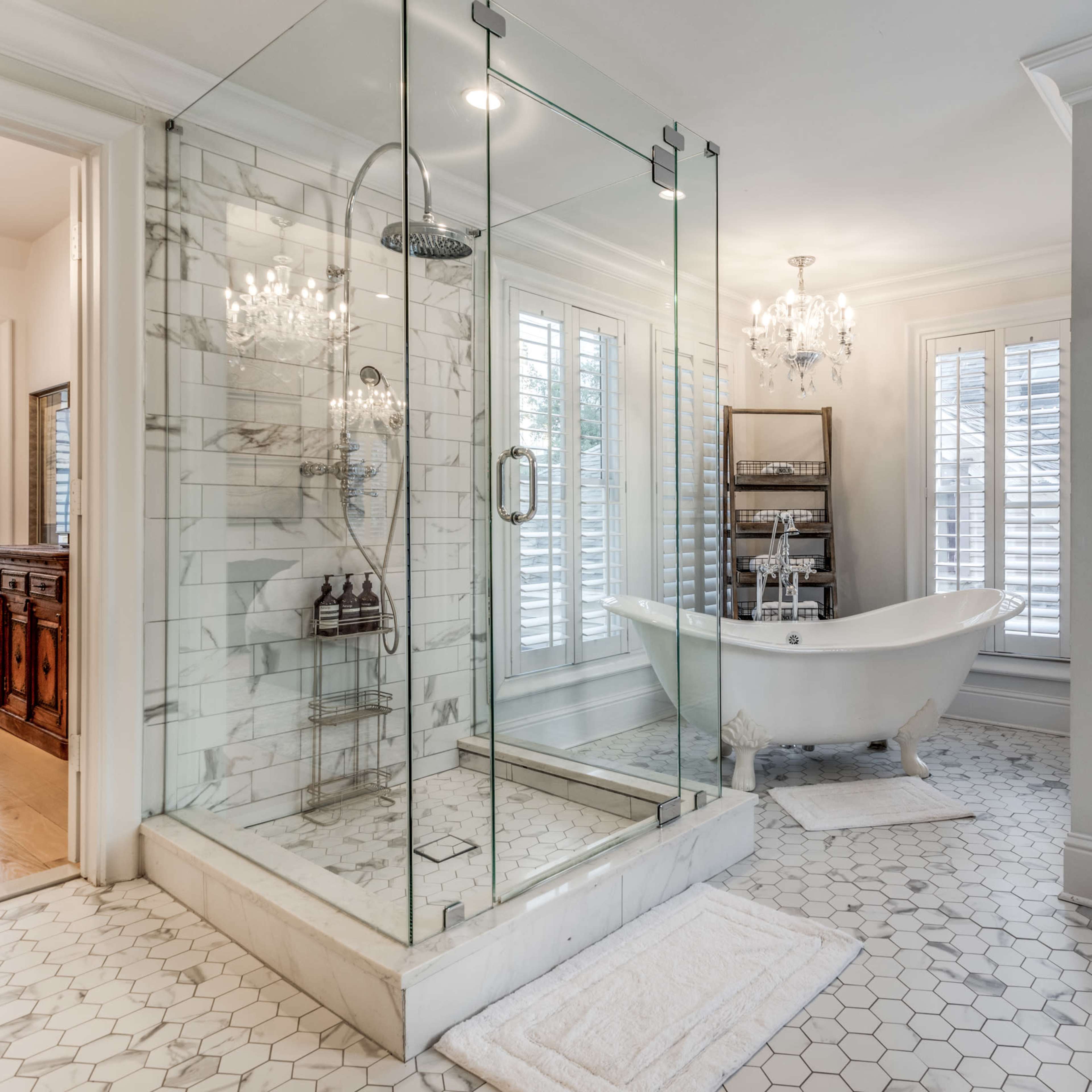 The bathroom features a glass shower enclosure, a freestanding bathtub, and decorative lighting fixtures, all arranged with tiled flooring and modern amenities.
