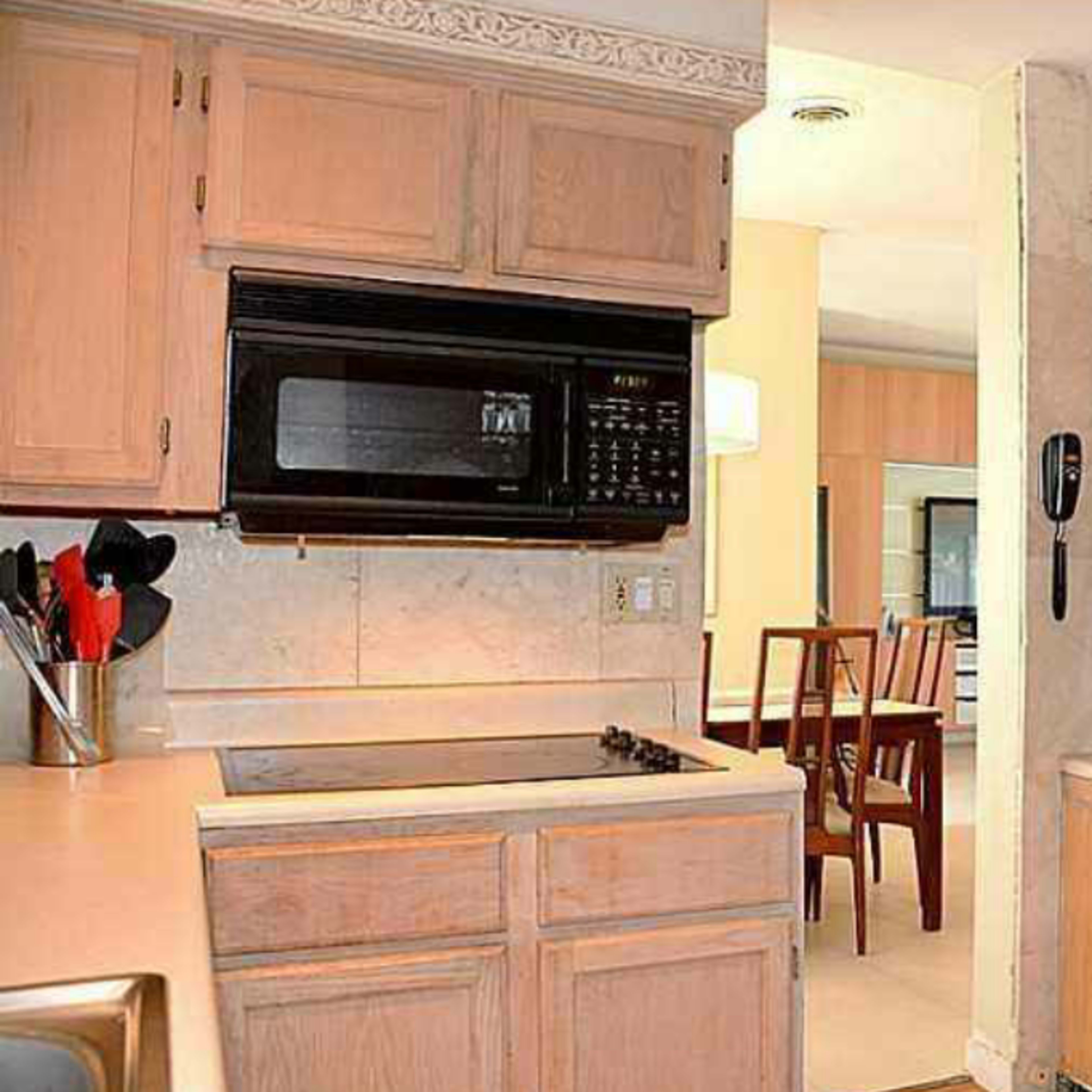 A kitchen with wooden cabinets, a microwave above the stove, and various kitchen appliances on the countertop.