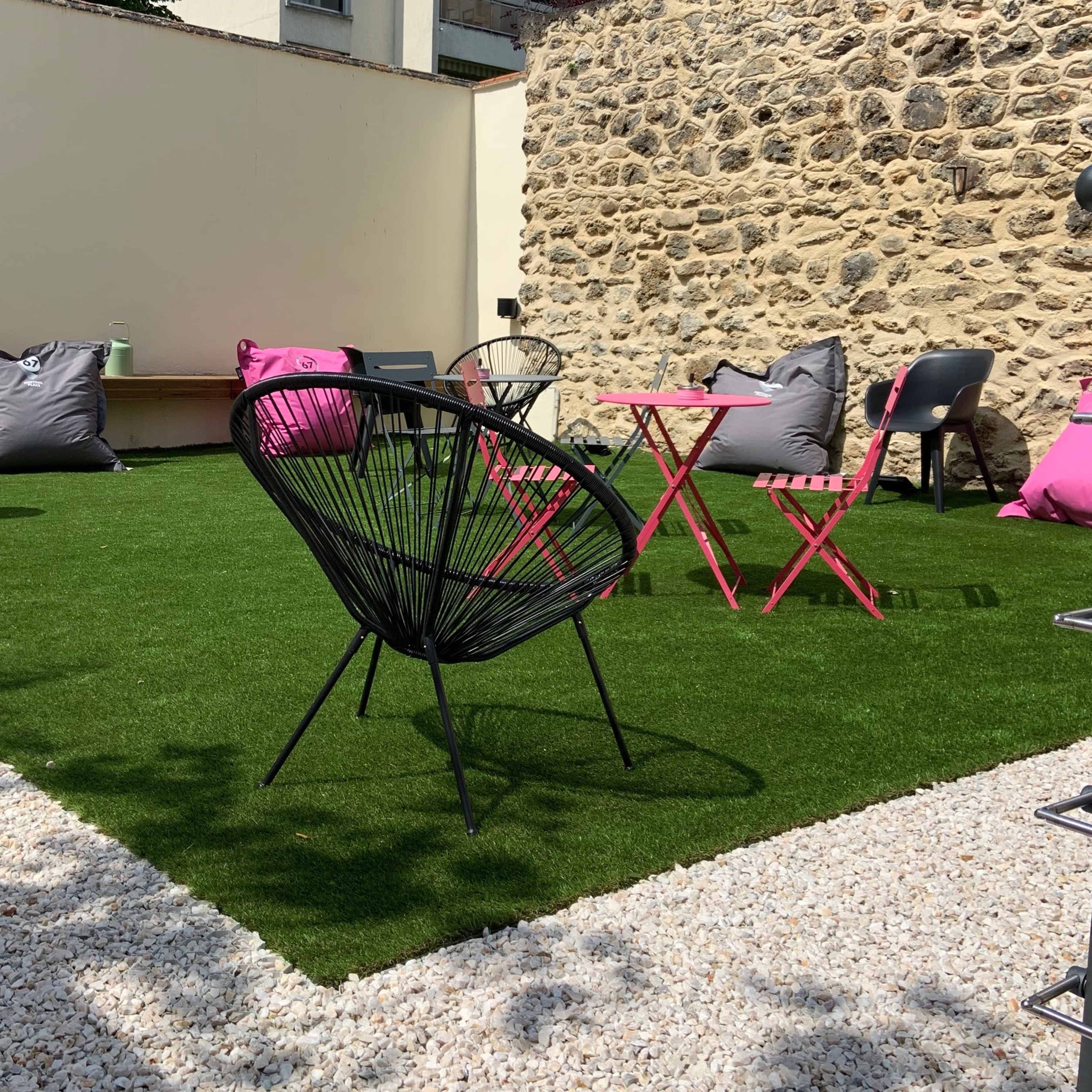 The scene features a small outdoor space with artificial grass, a black chair, pink bean bags, and a soccer ball.