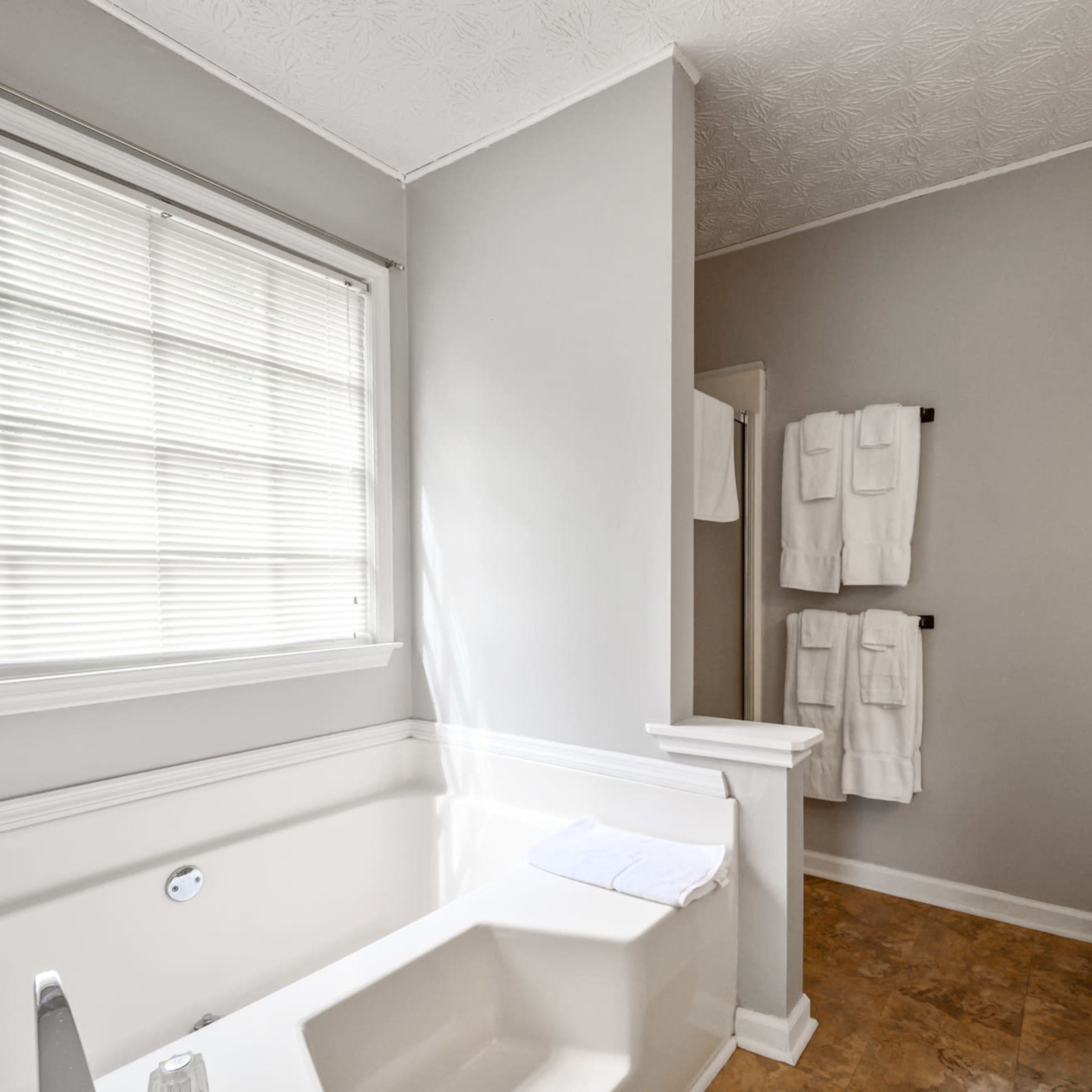 A bathroom featuring a bathtub, a toilet, and towels hanging on the wall.