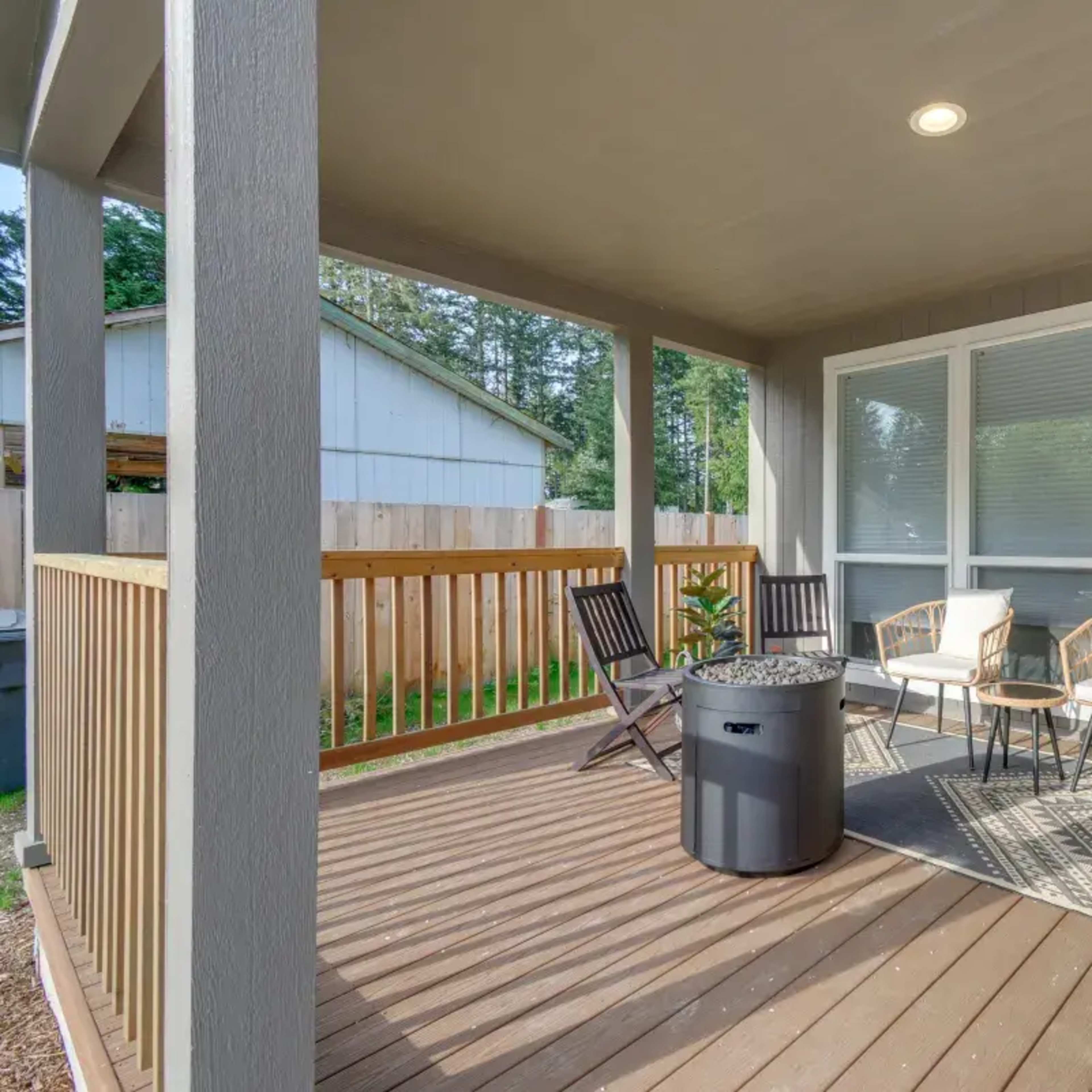 A covered porch featuring a seating arrangement with two chairs and a round table, surrounded by wooden railings.