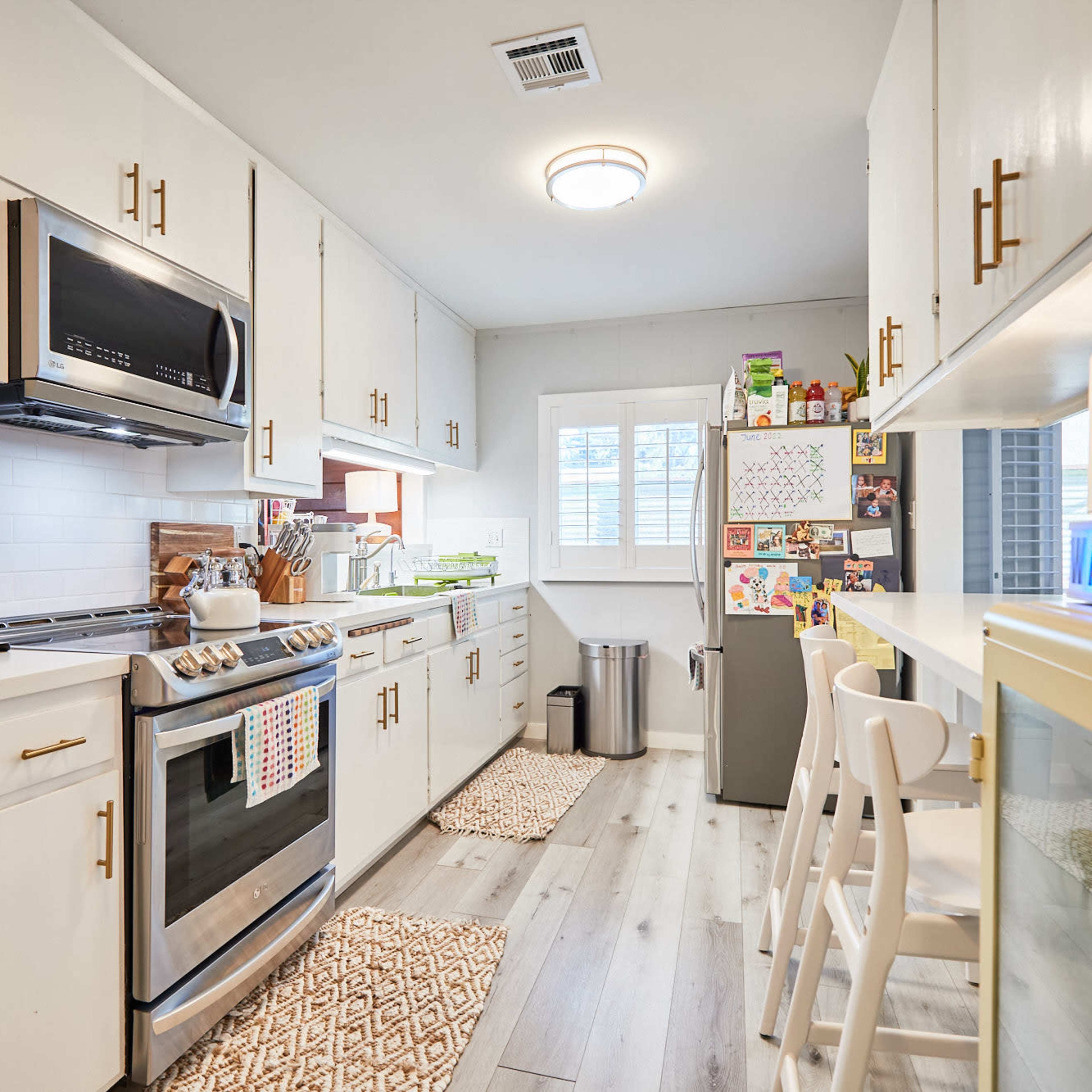 A modern kitchen with white cabinets, stainless steel appliances, and a small dining area featuring a table and chairs.