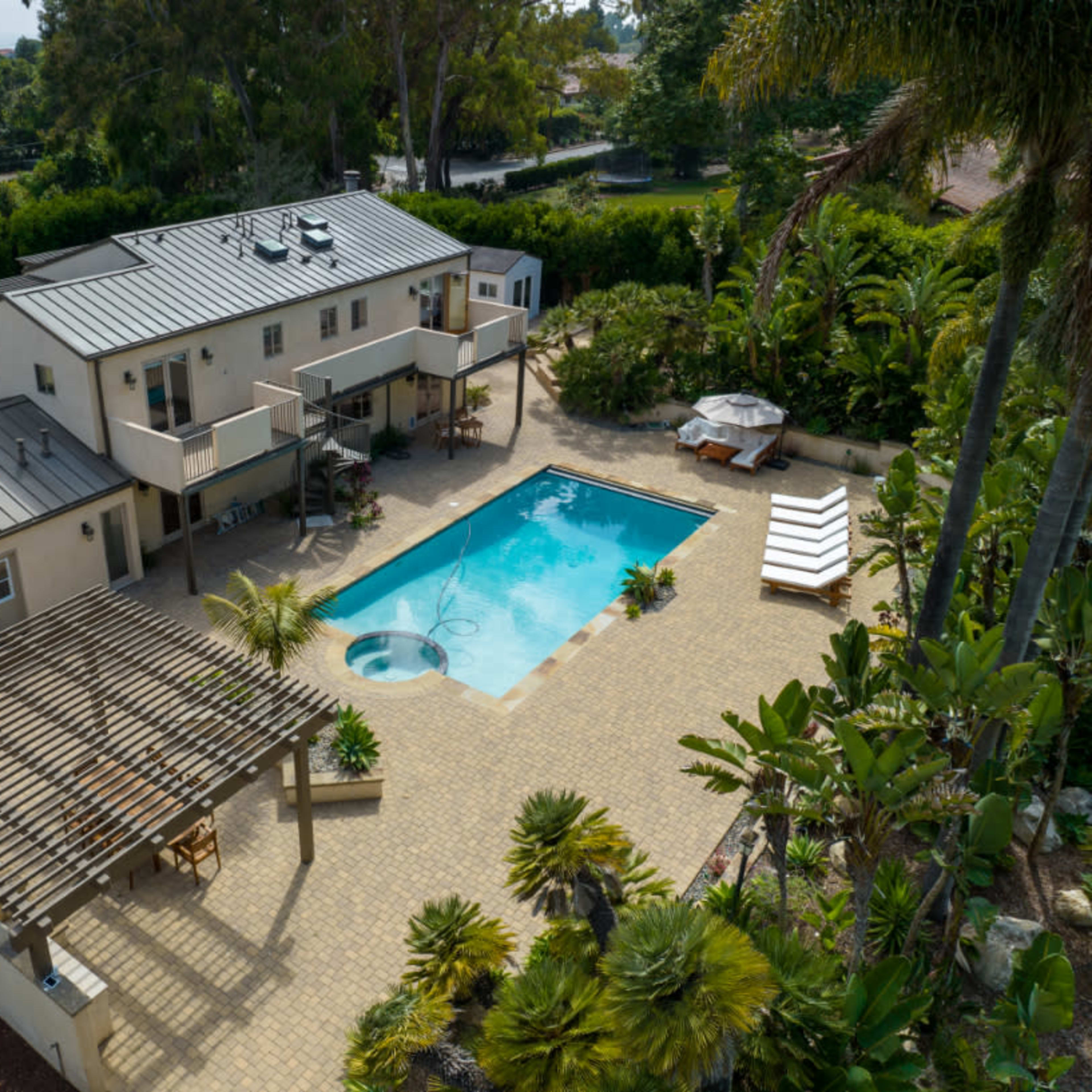 A modern house with a swimming pool, surrounded by landscaped gardens and outdoor seating areas.