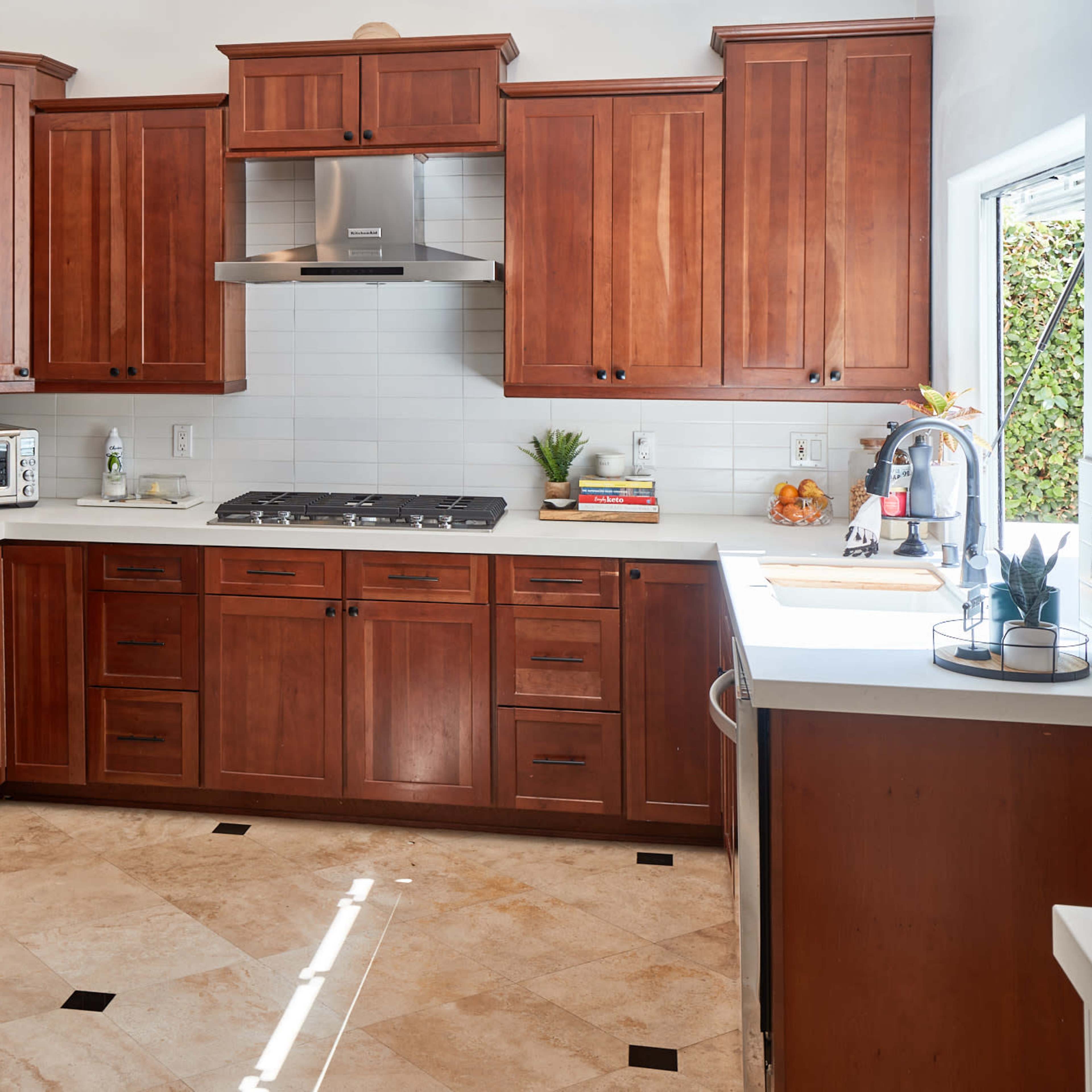 A kitchen with wooden cabinetry, stainless steel appliances, and a tiled floor.