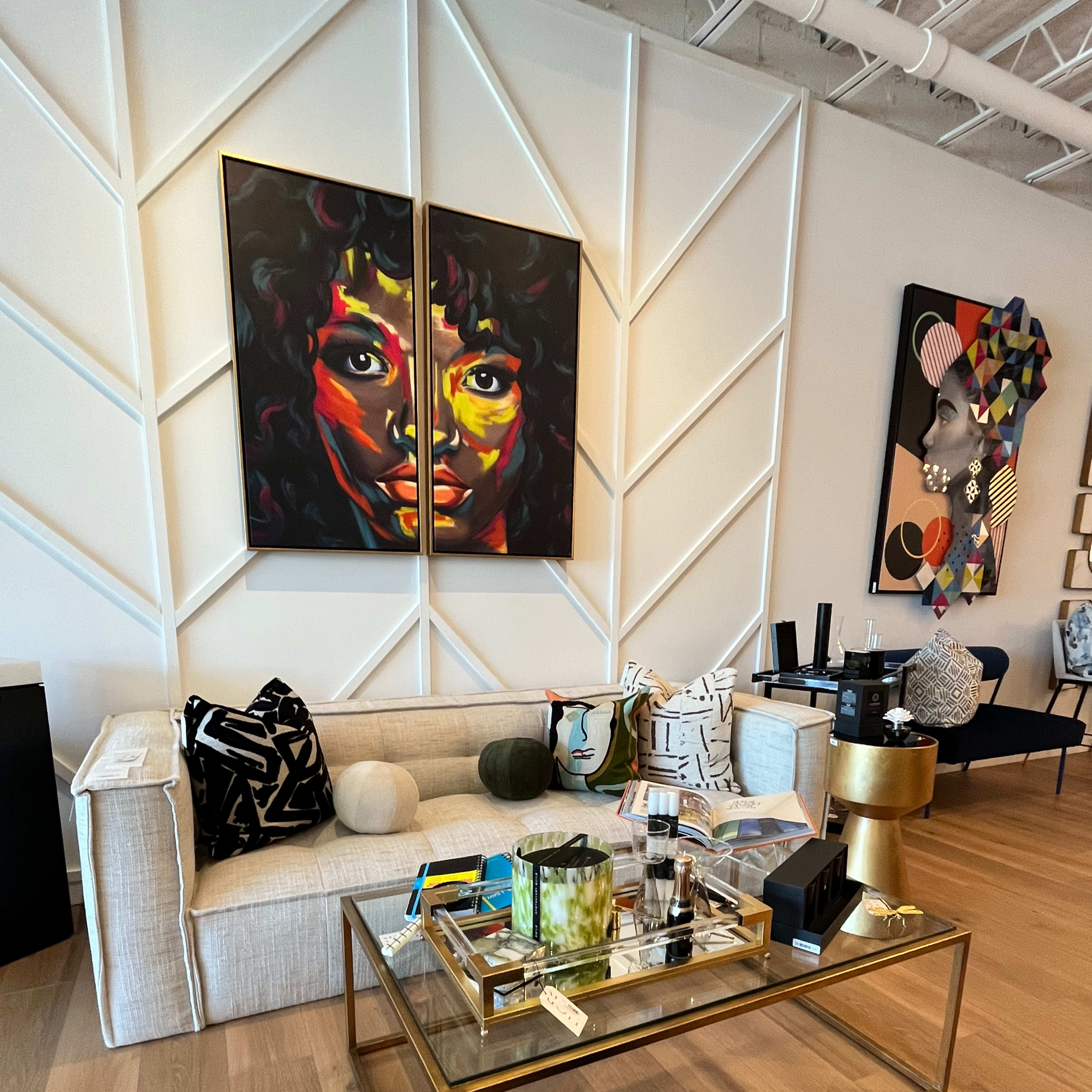 A stylish living room with a light-colored sofa, a gold-framed coffee table adorned with decorative items, and vibrant art pieces on the walls.