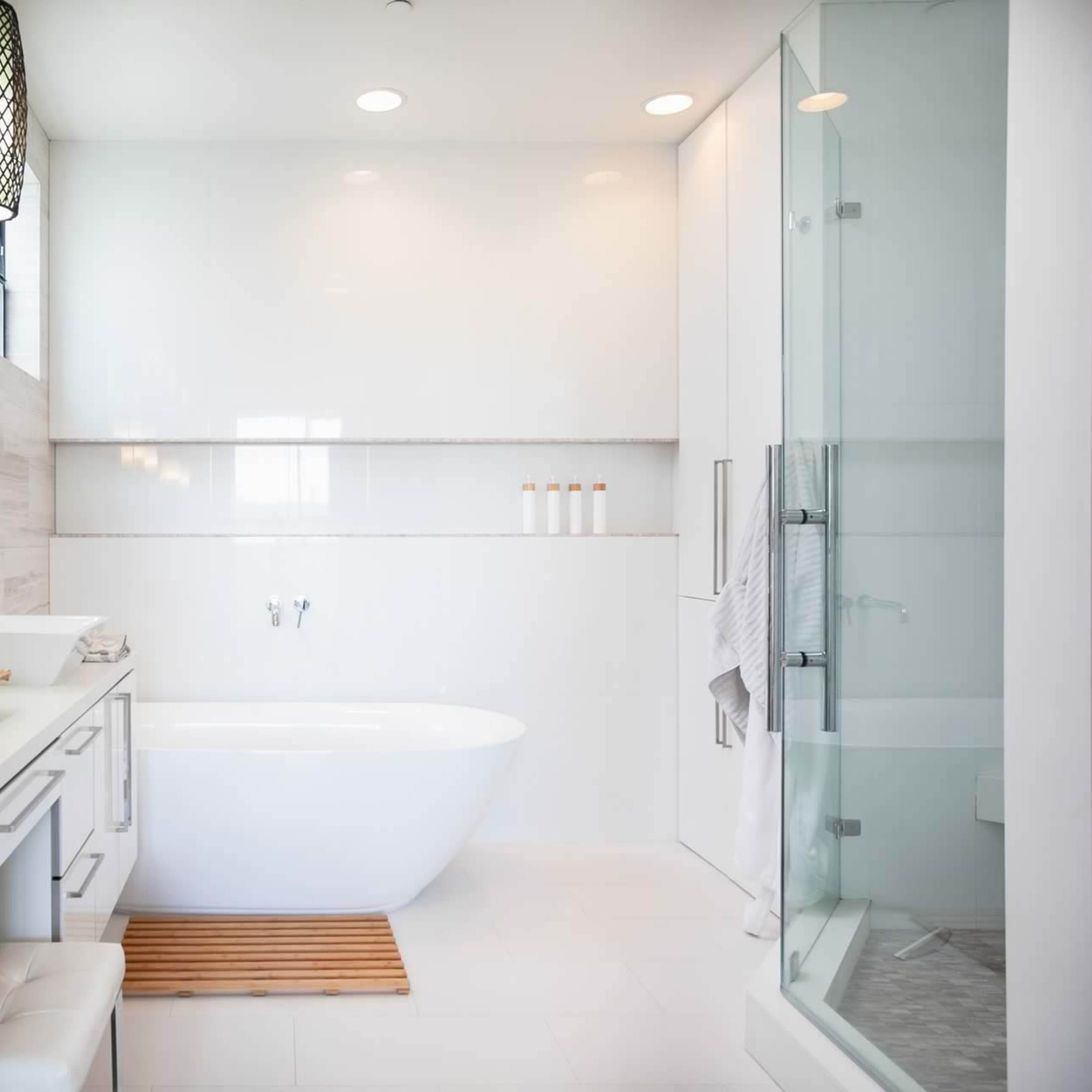 A modern bathroom featuring a freestanding bathtub, dual sinks with a basket for toiletries, and a glass shower enclosure.