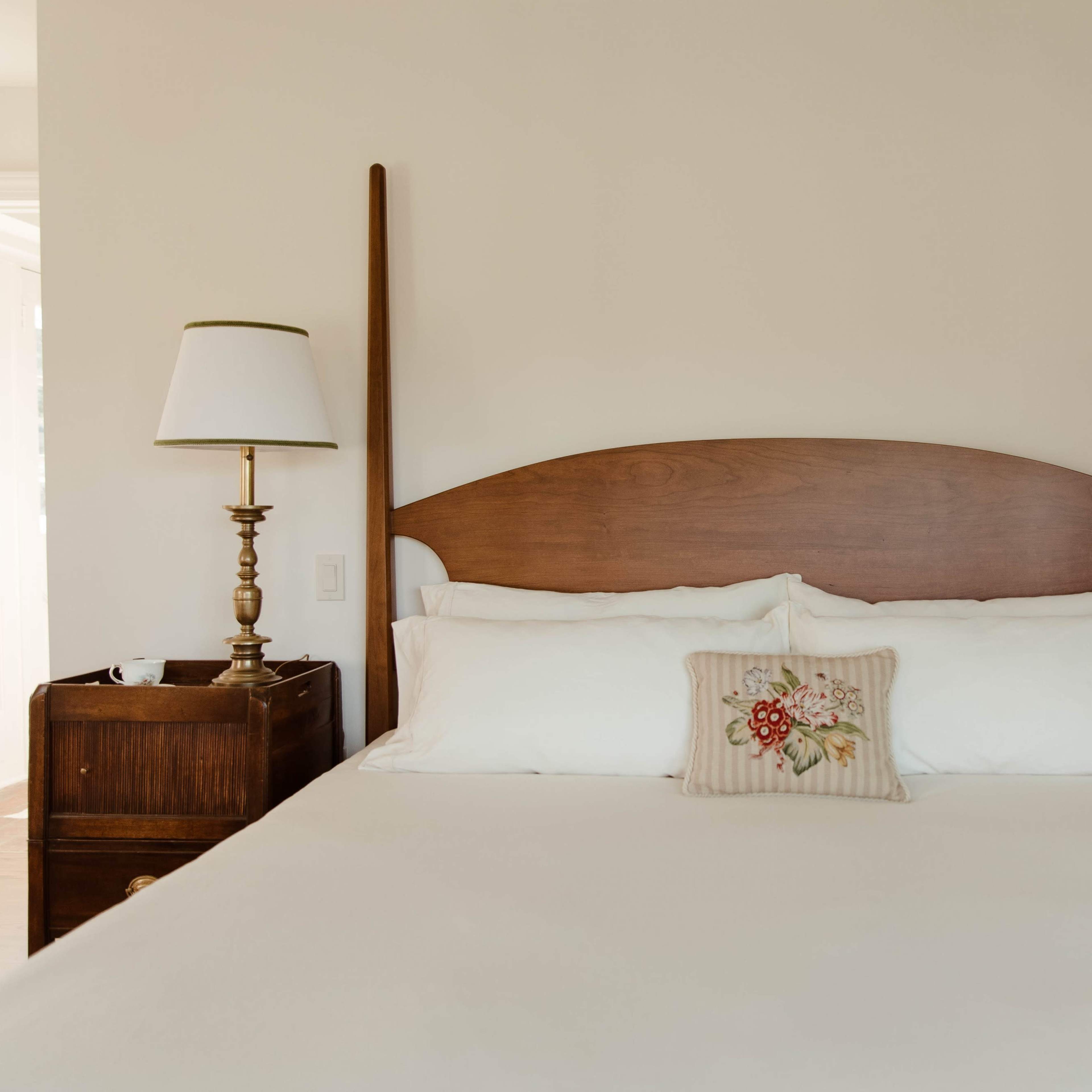 A neatly made bed with a wooden headboard, flanked by two bedside tables and reading lamps.