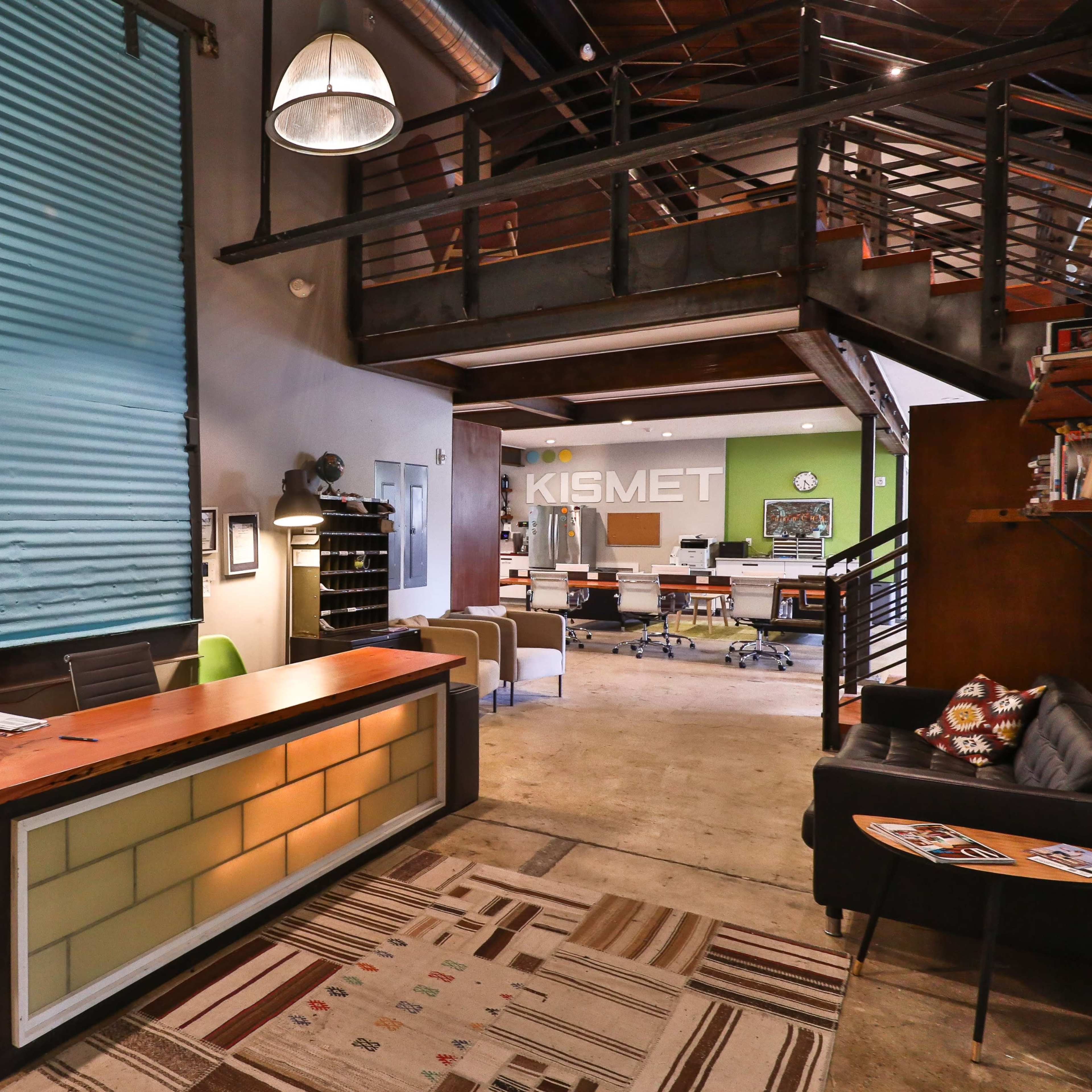 A modern office reception area featuring a wooden desk, a bicycle, and a spacious open workspace in the background.